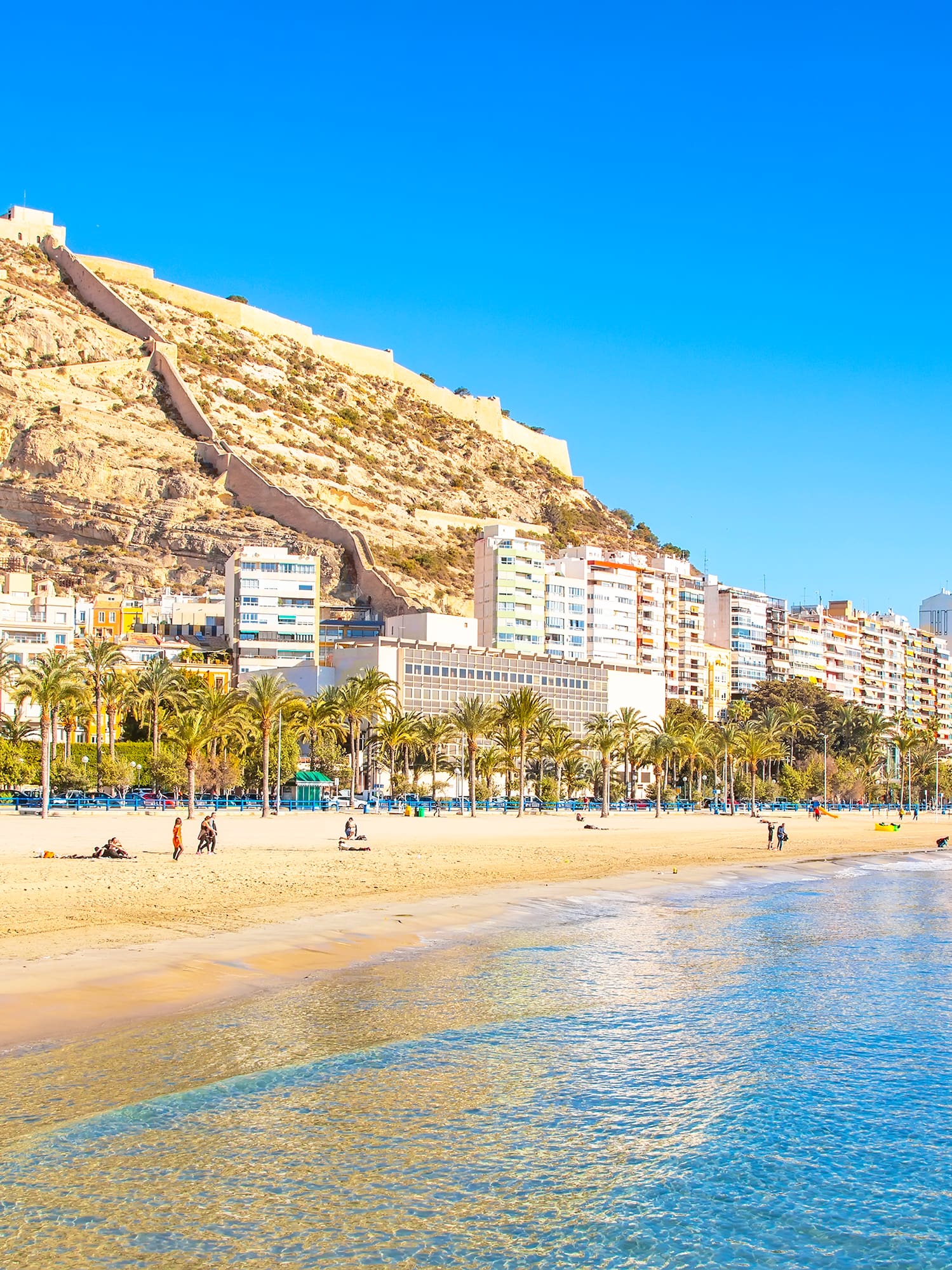 a beach with buildings and a hill