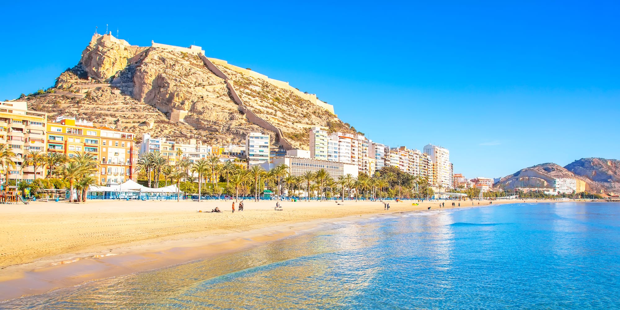 a beach with buildings and a hill