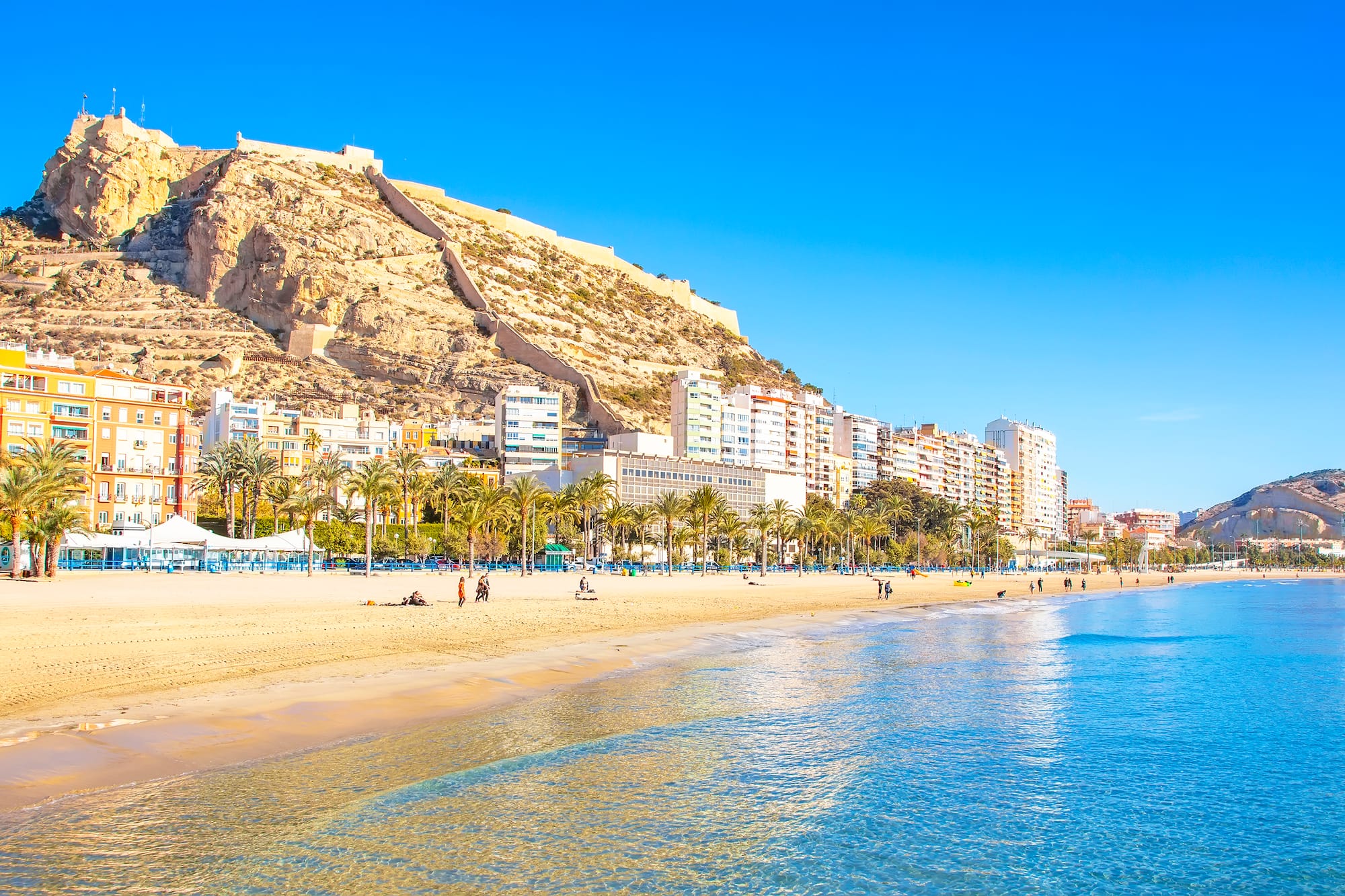 a beach with buildings and a hill