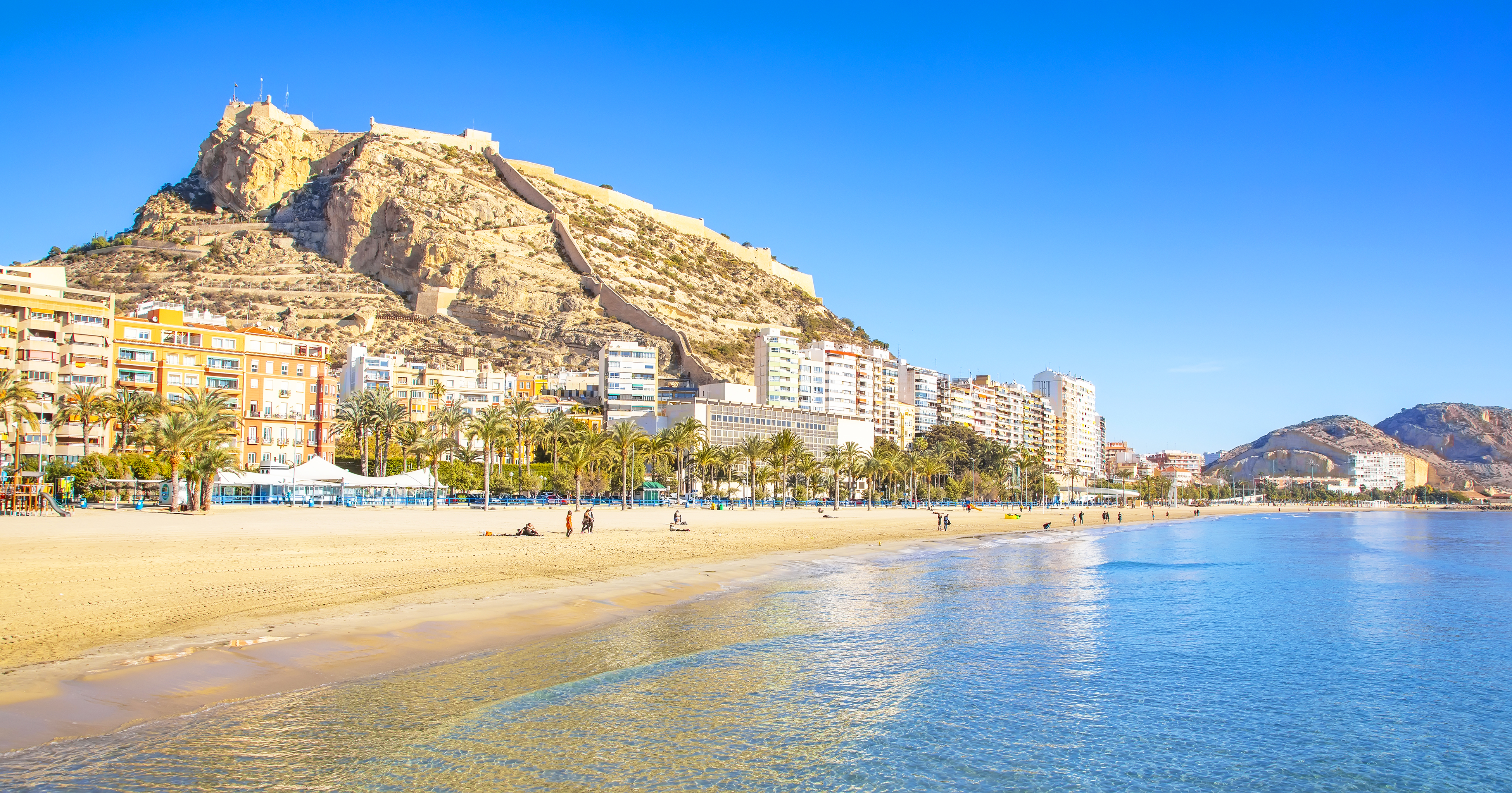 a beach with buildings and a hill