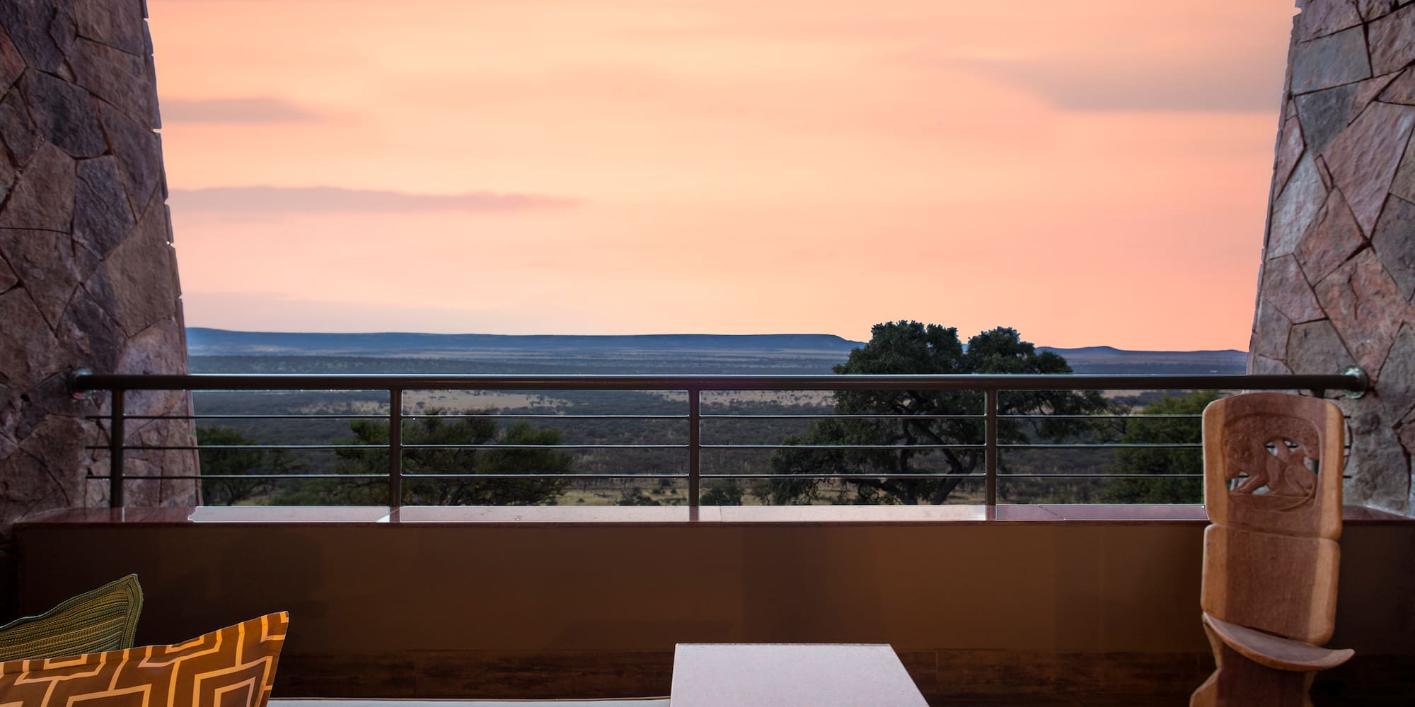 a table and chair on a balcony with a view of the landscape