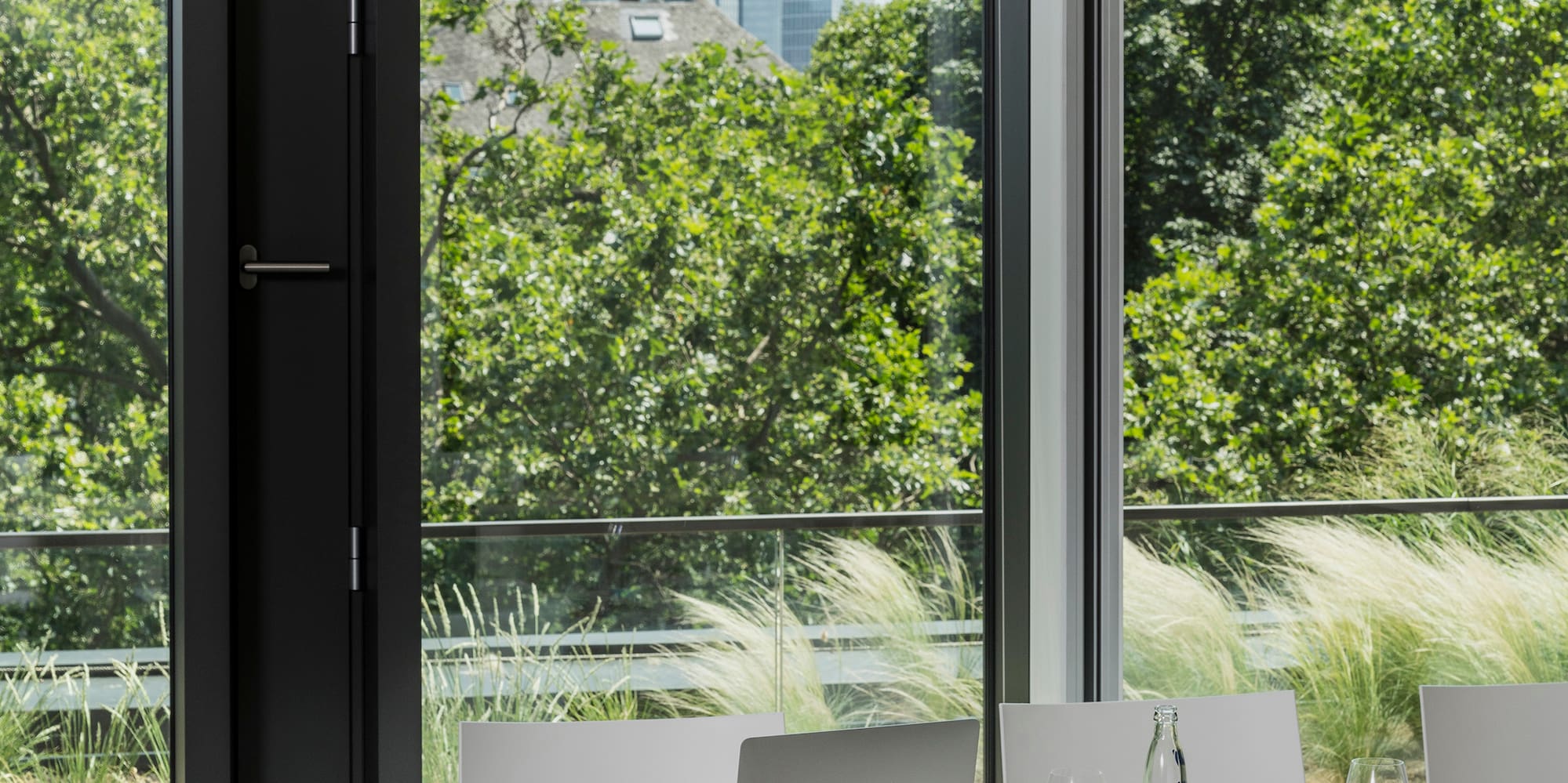 a table with chairs and laptops in a room with trees and a city view