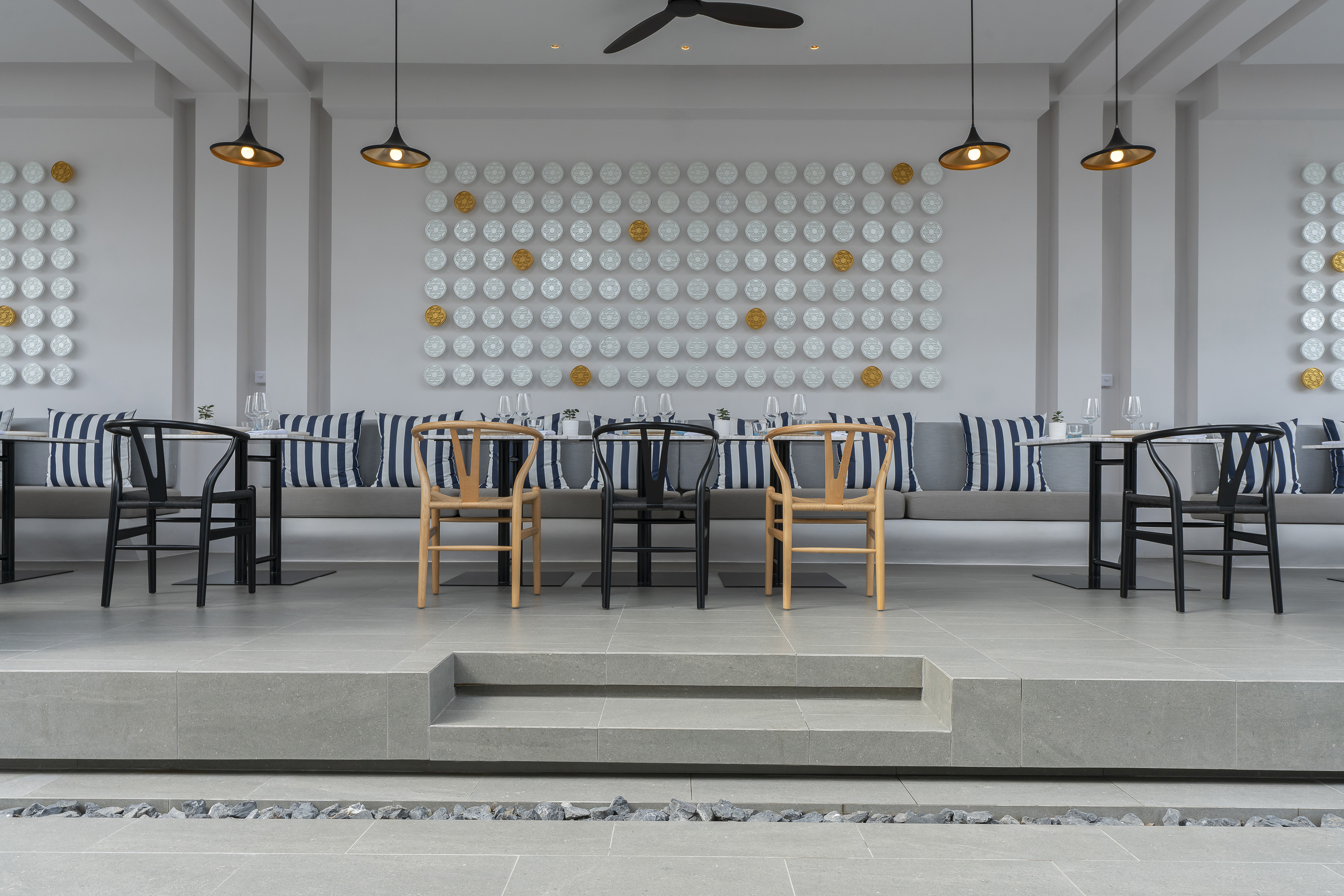 Modern restaurant dining area with striped cushions and decorative wall plates.