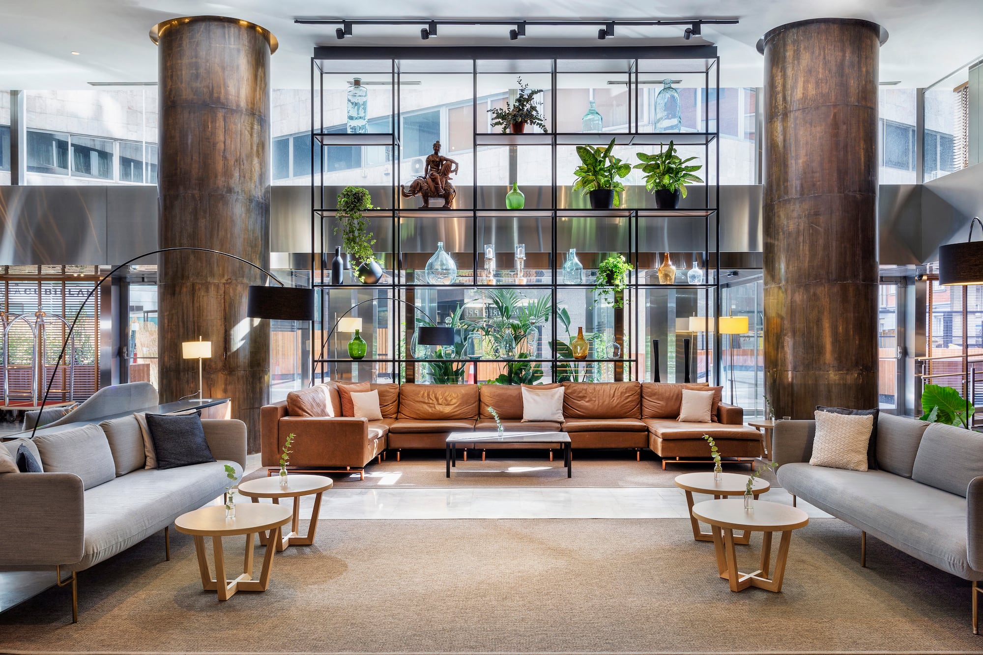 Contemporary hotel lounge with stylish seating, decorative shelf, and tall columns.