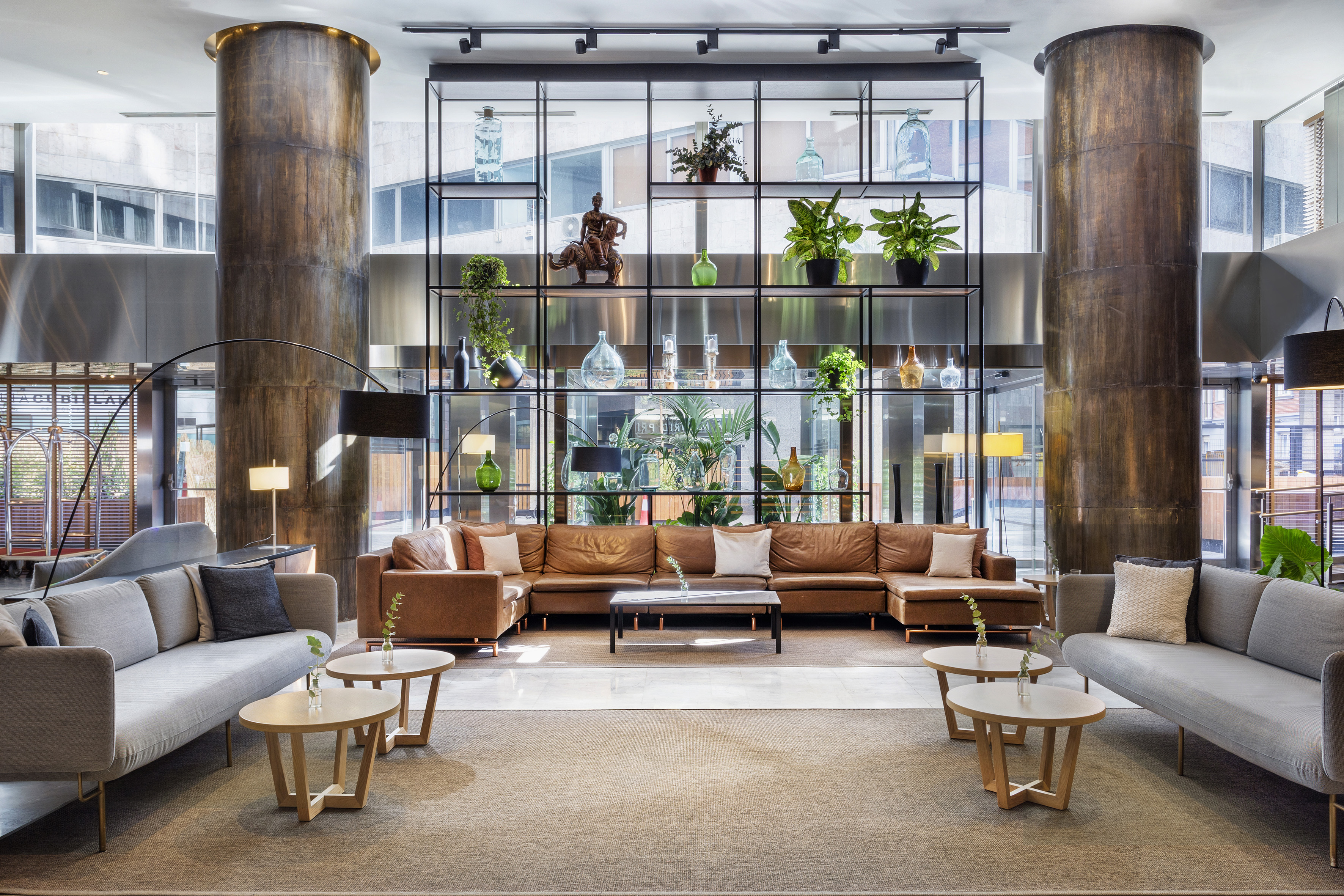 Contemporary hotel lounge with stylish seating, decorative shelf, and tall columns.