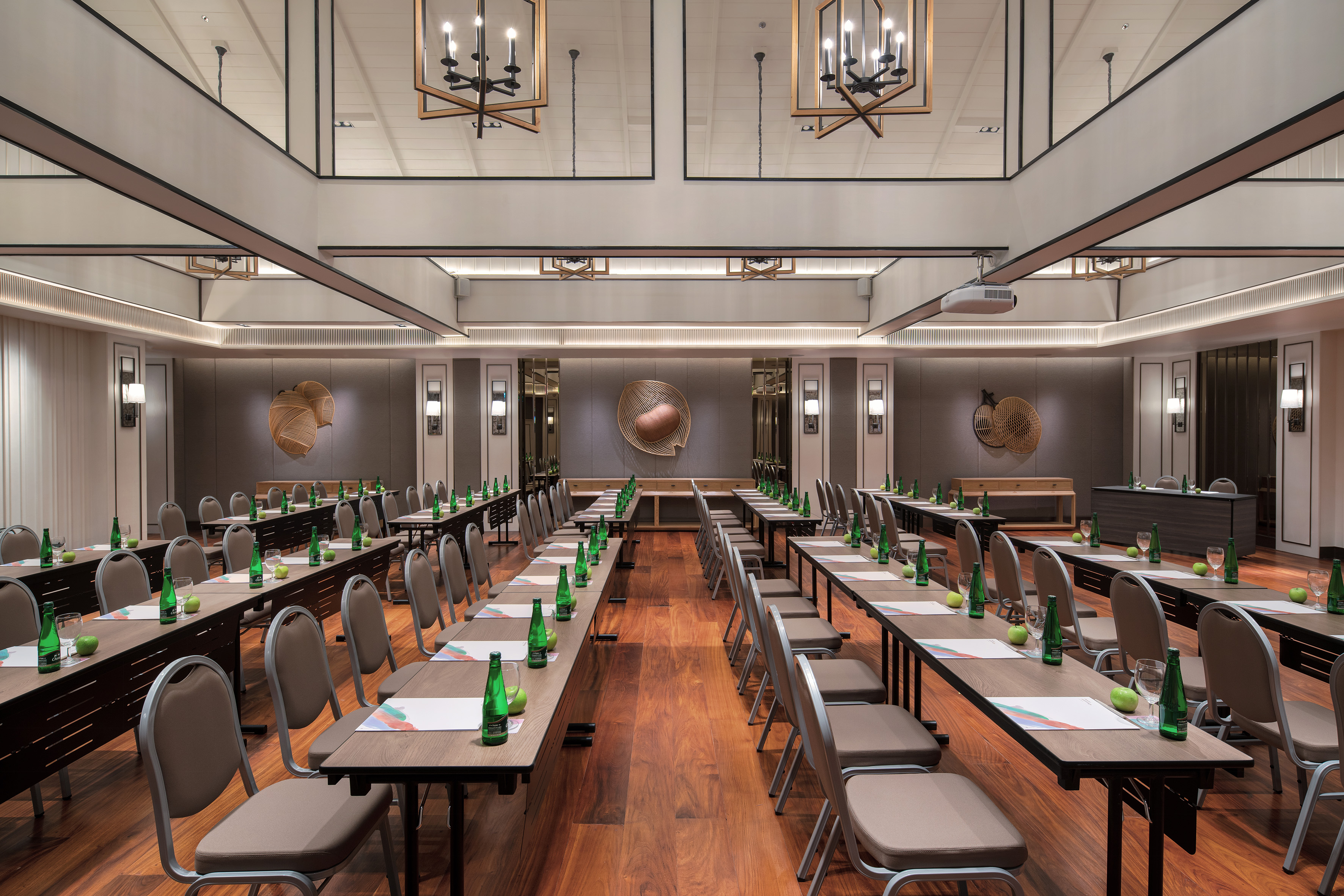 Spacious modern conference room with tables, chairs, projector, and chandeliers.