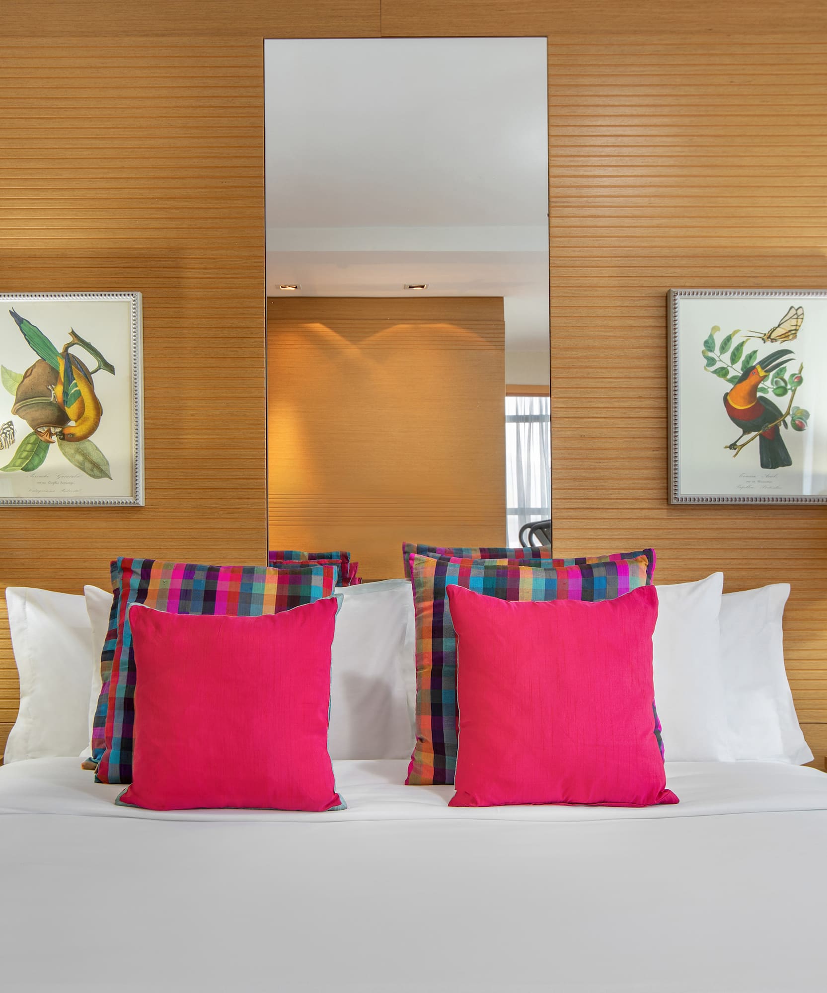 a bed with pink pillows and a mirror on the wall