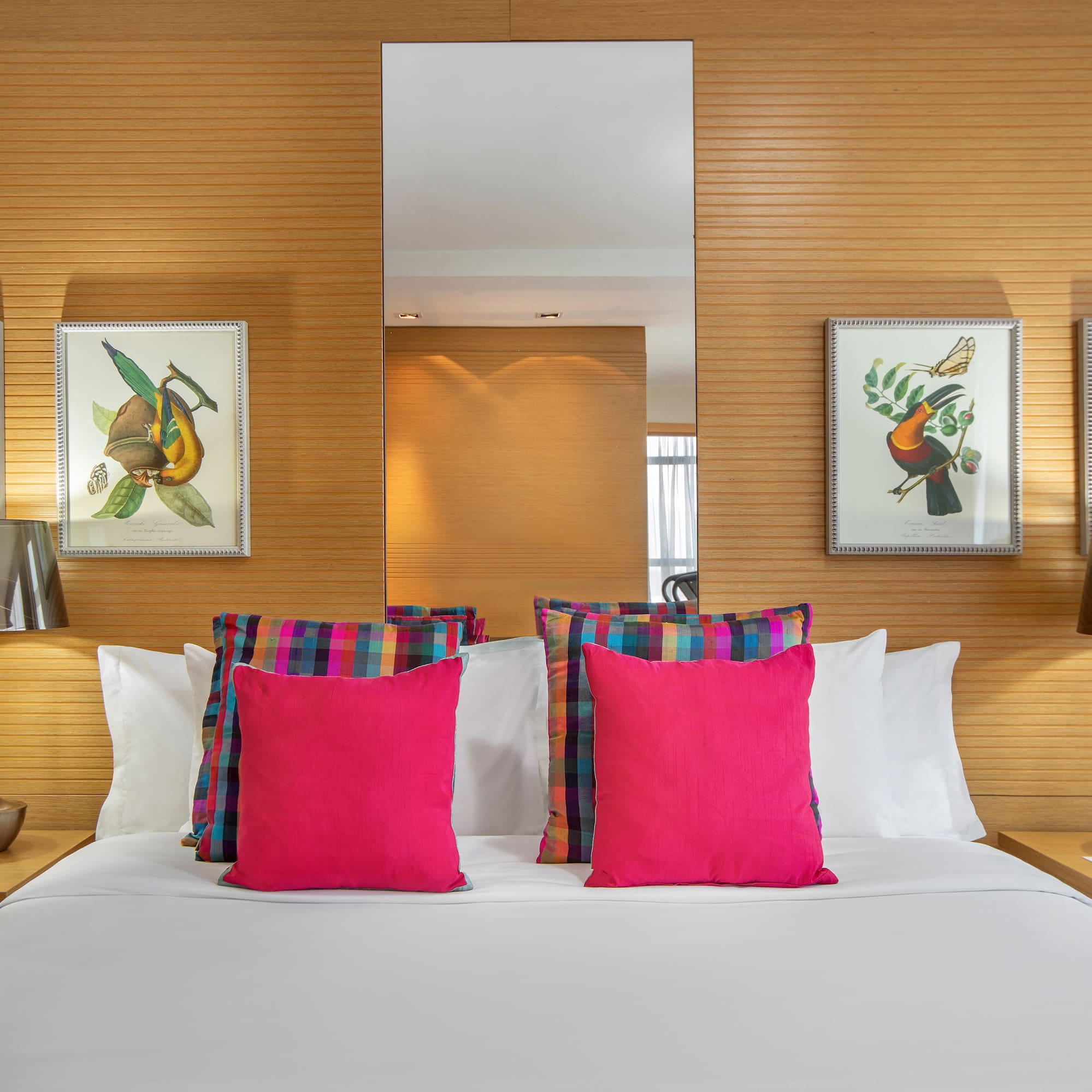 a bed with pink pillows and a mirror on the wall