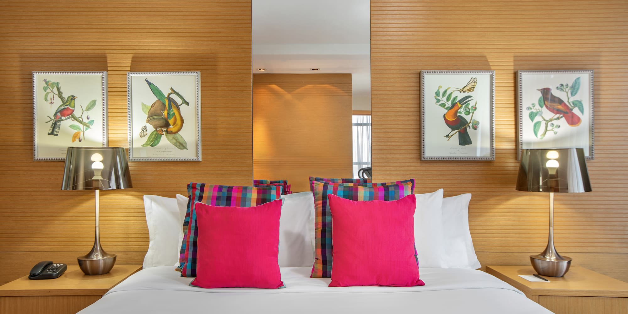 a bed with pink pillows and a mirror on the wall