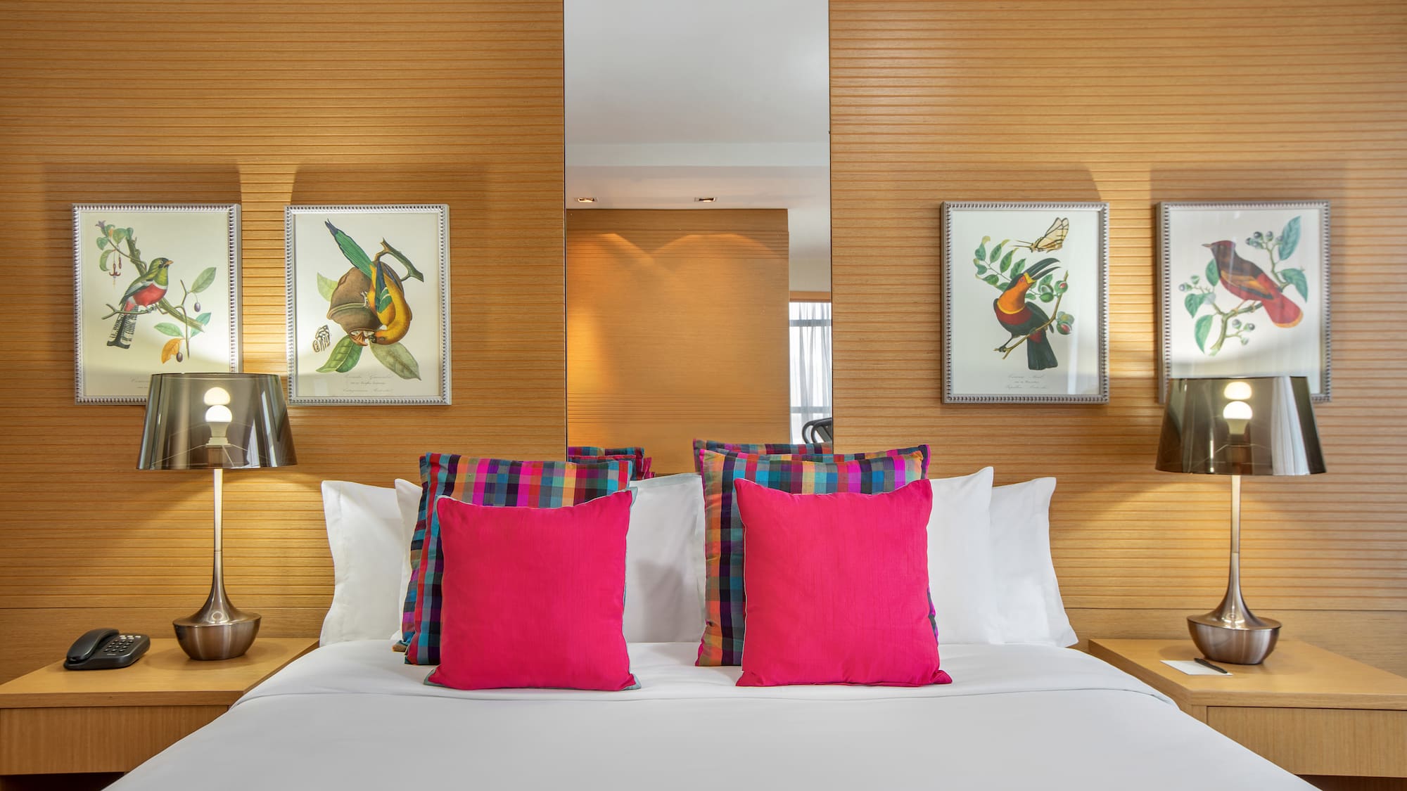 a bed with pink pillows and a mirror on the wall