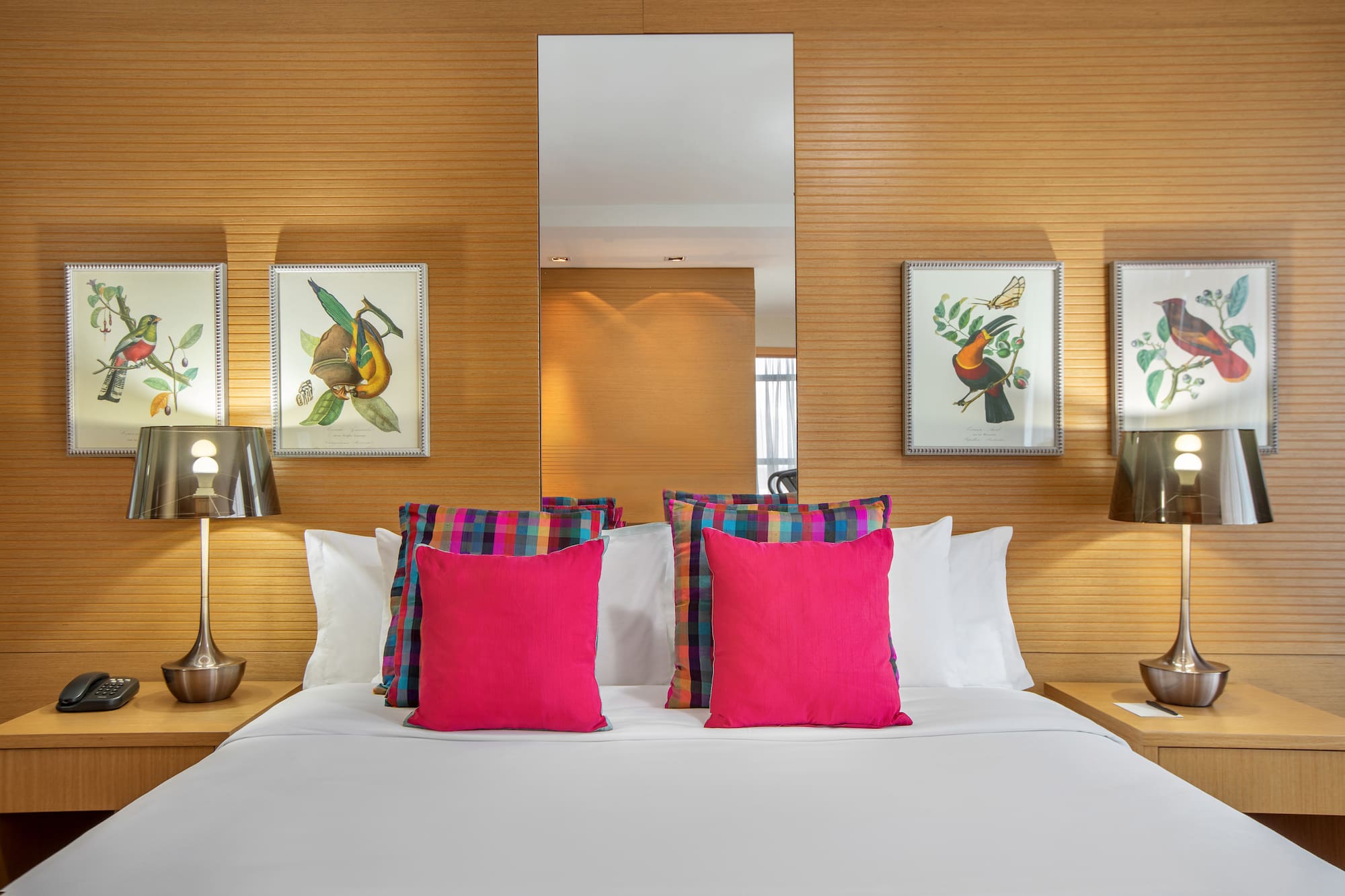 a bed with pink pillows and a mirror on the wall