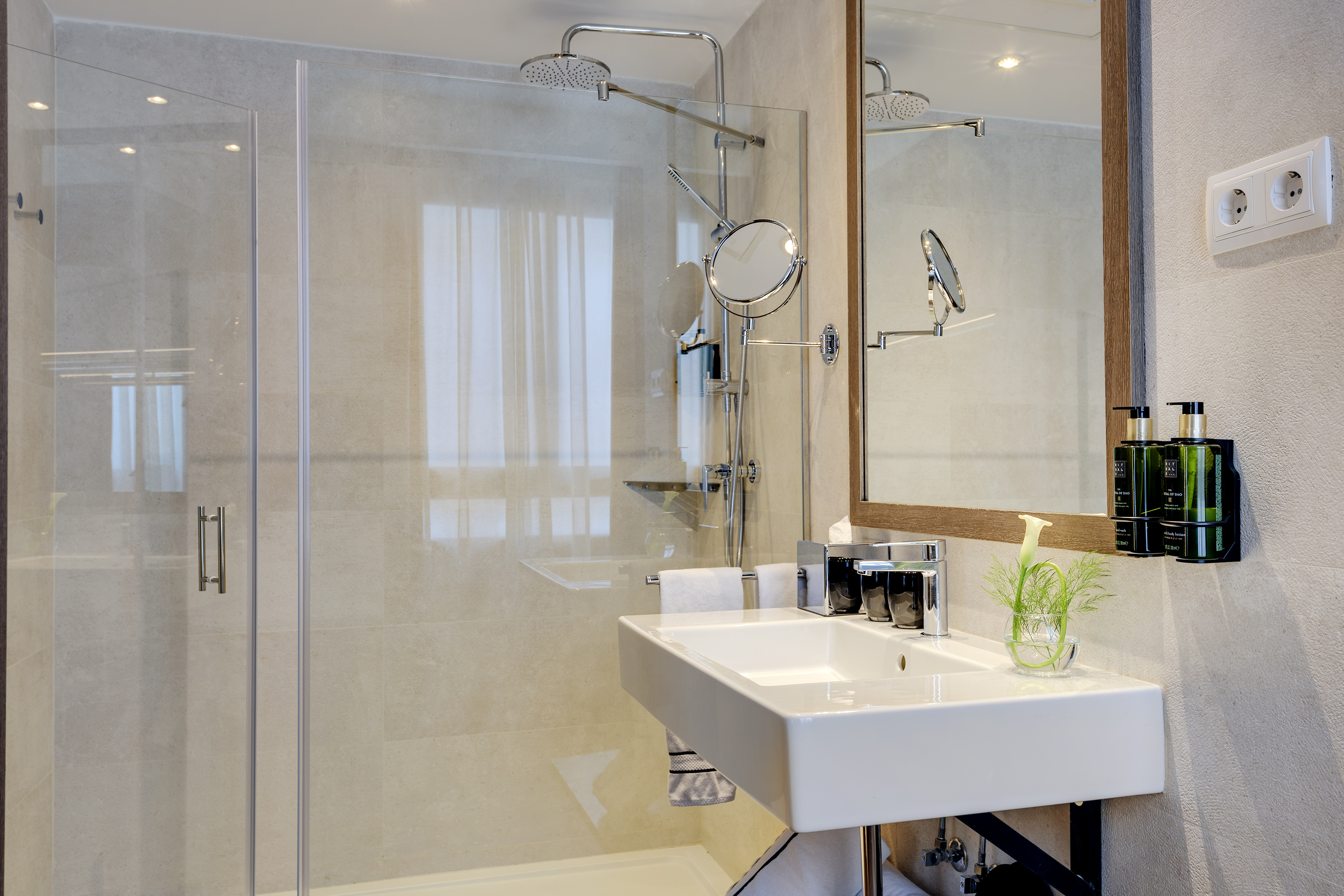 Modern bathroom with glass shower, white vanity sink, and large mirror.
