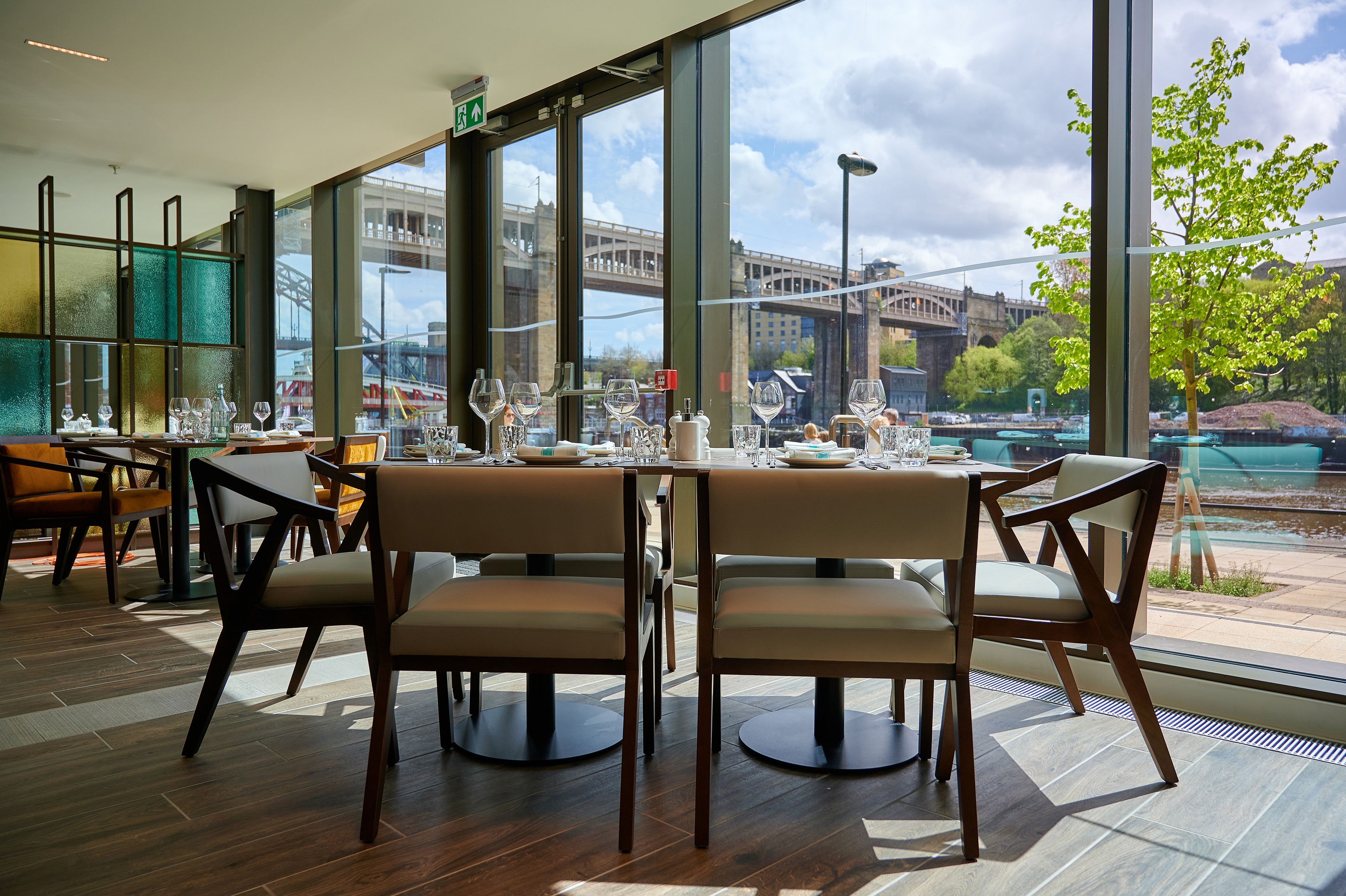 Restaurant dining with set tables, window view of Tyne Bridge and river.