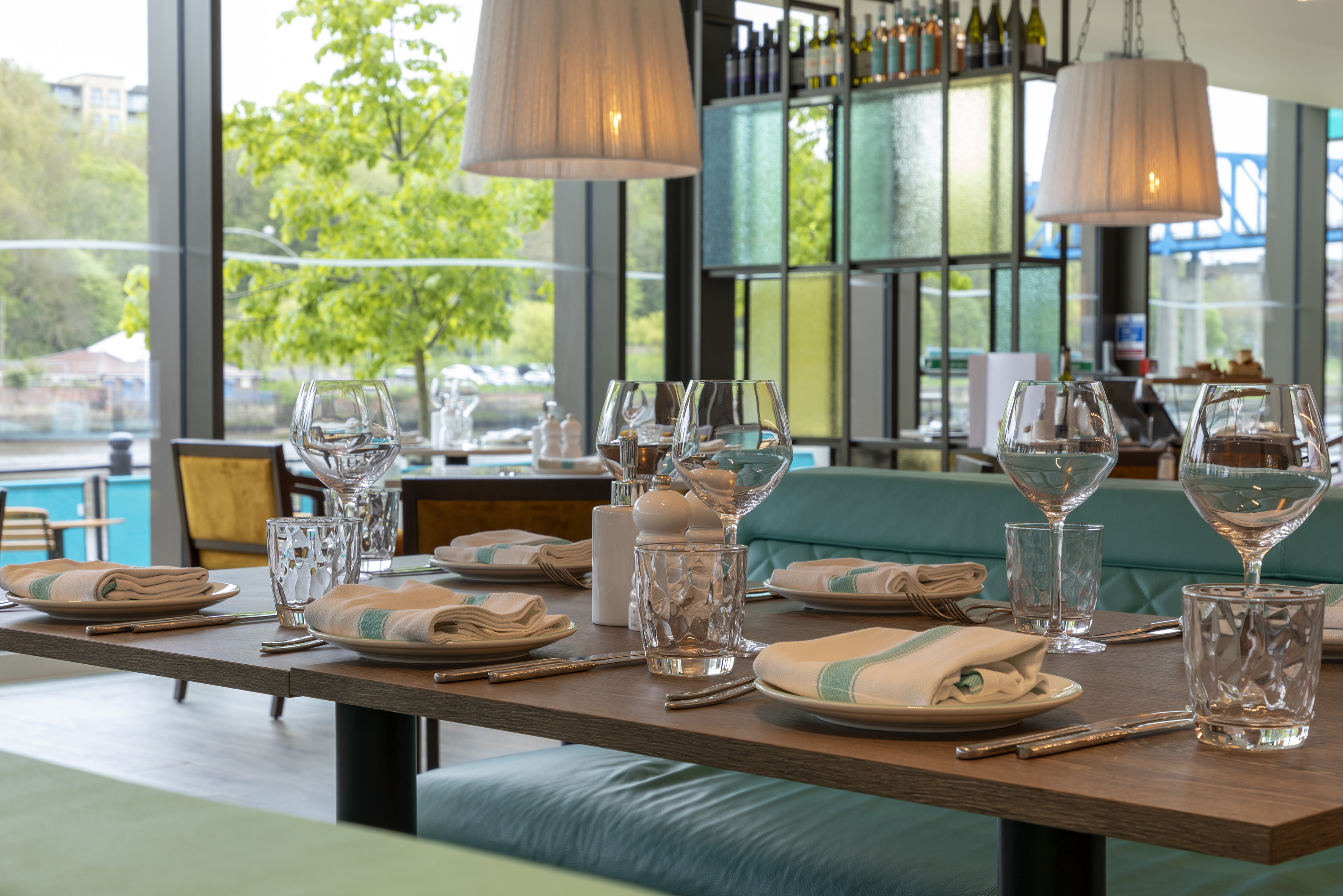 Set dining table in a modern restaurant with waterfront window view.