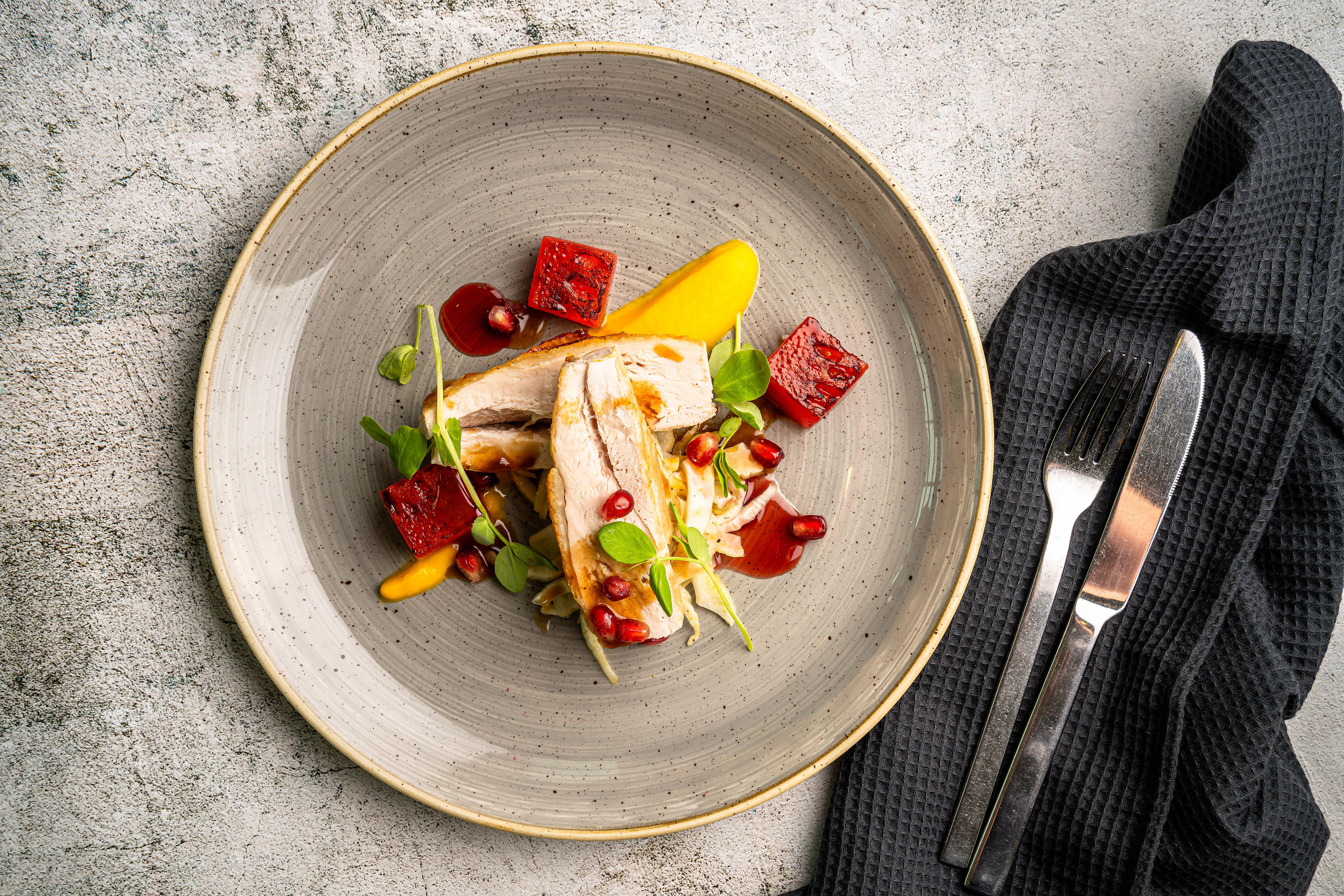 Gourmet chicken breast with roasted beetroot, yellow puree, and pomegranate on a plate.