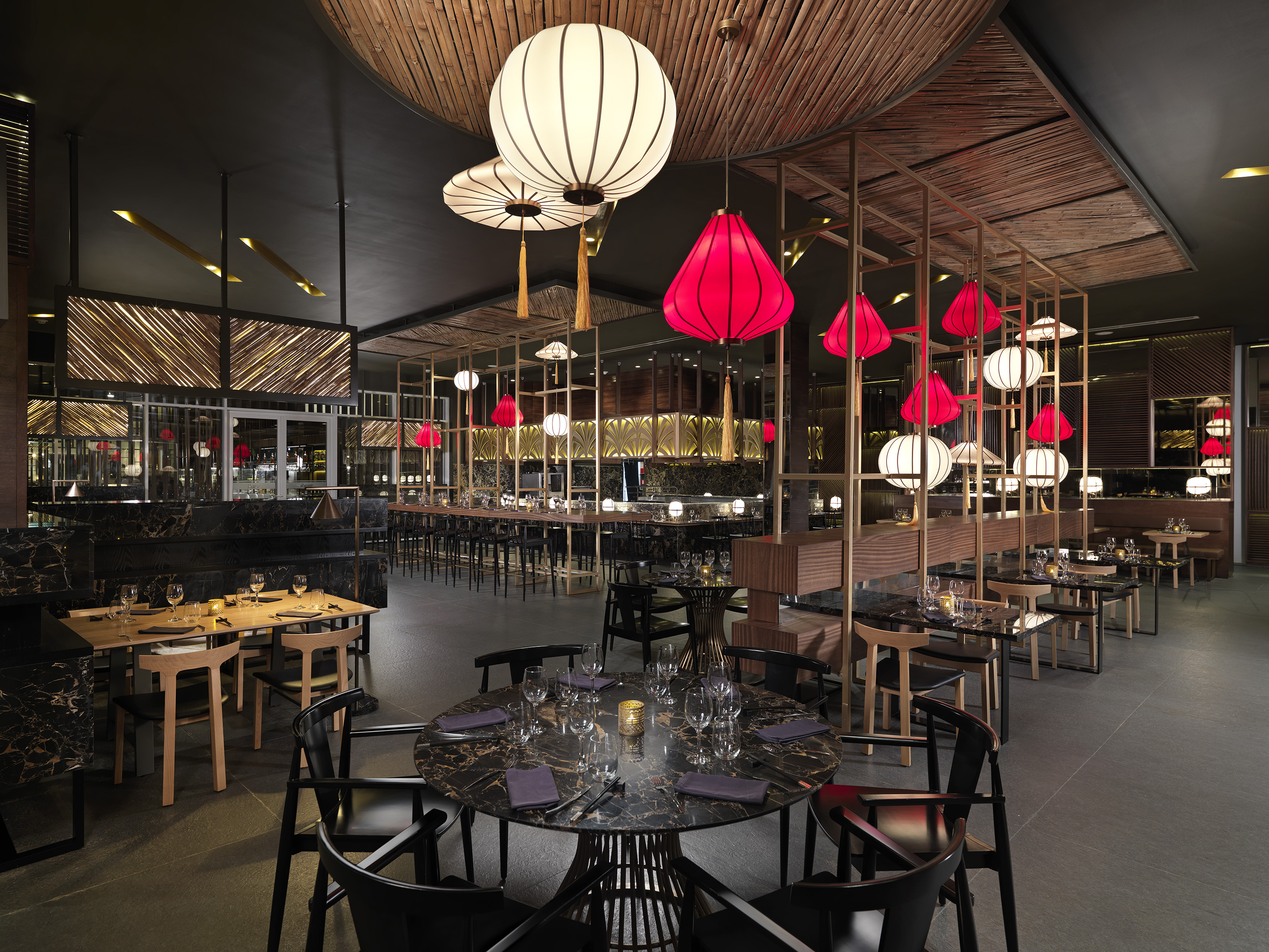 Modern Asian restaurant interior with red lanterns and bamboo ceiling.