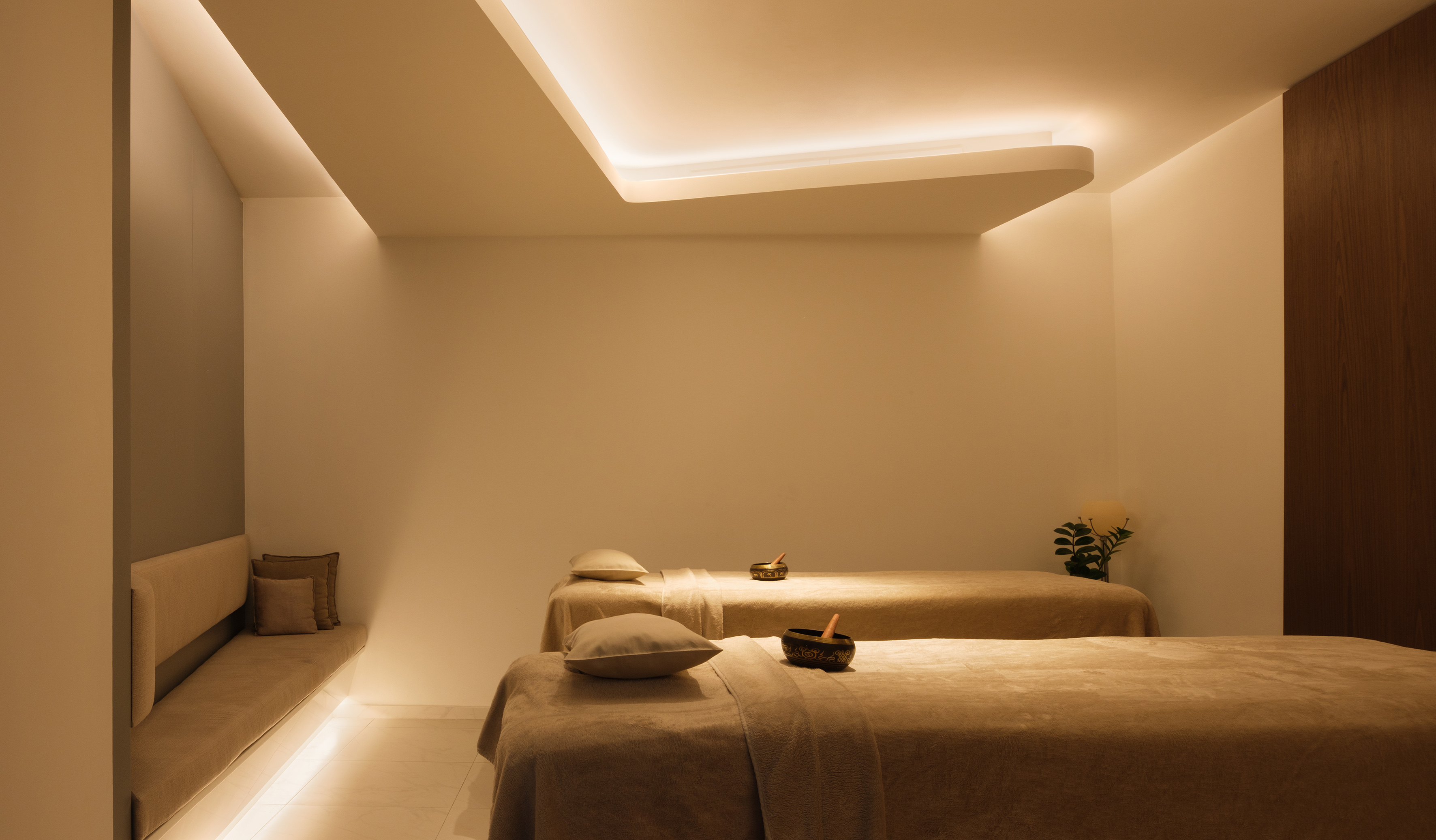 Spa treatment room, two massage beds, warm lighting, singing bowls.