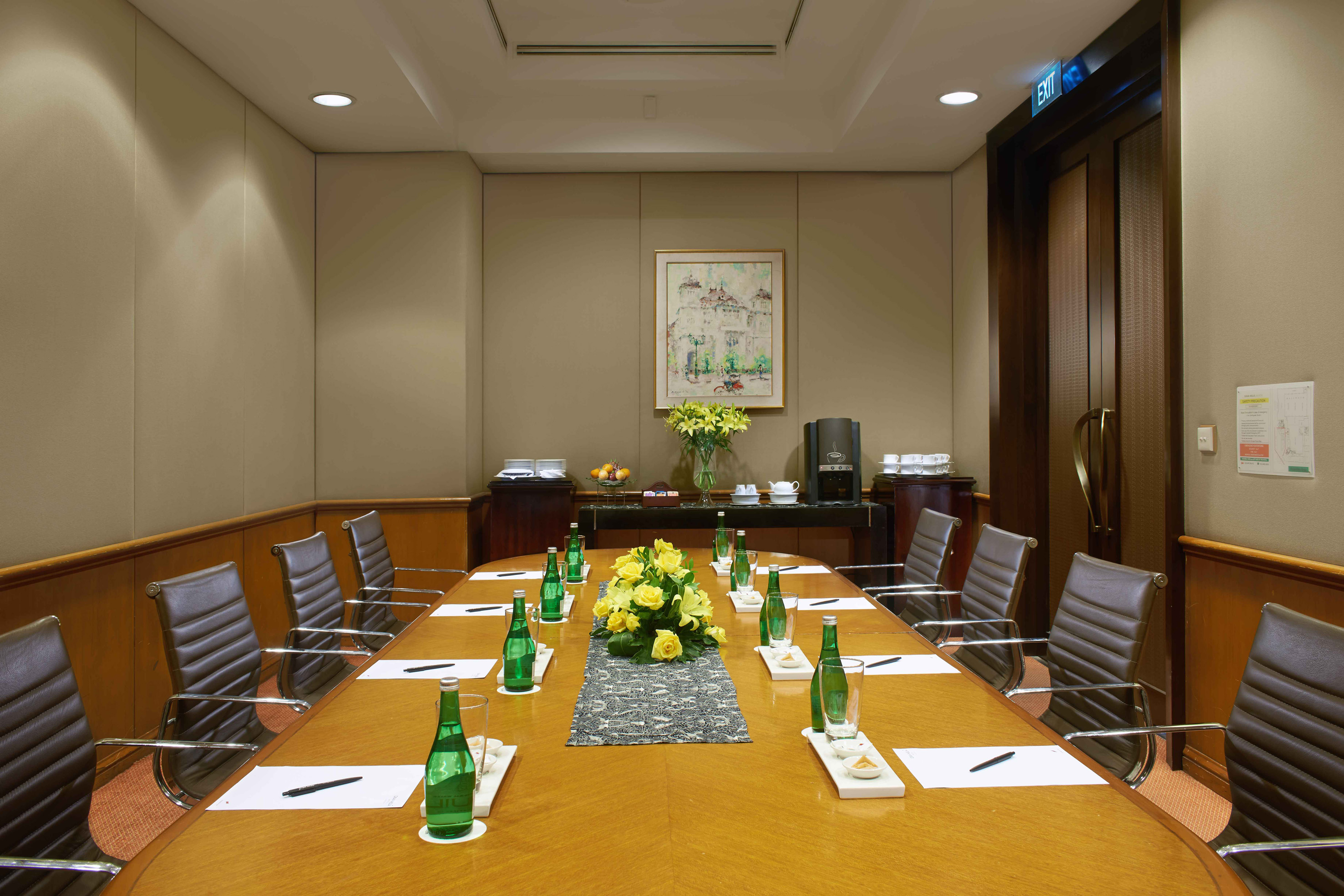 Elegant conference room with wooden table, brown chairs, water, and coffee setup.