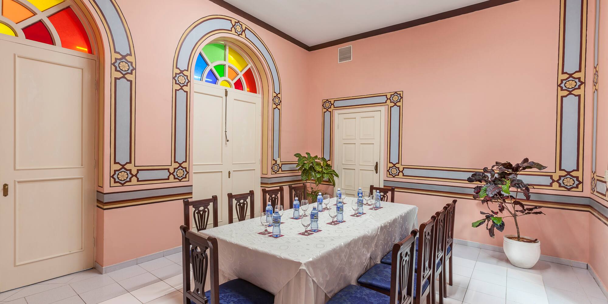 a table with chairs and a white tablecloth in a room with a pink wall