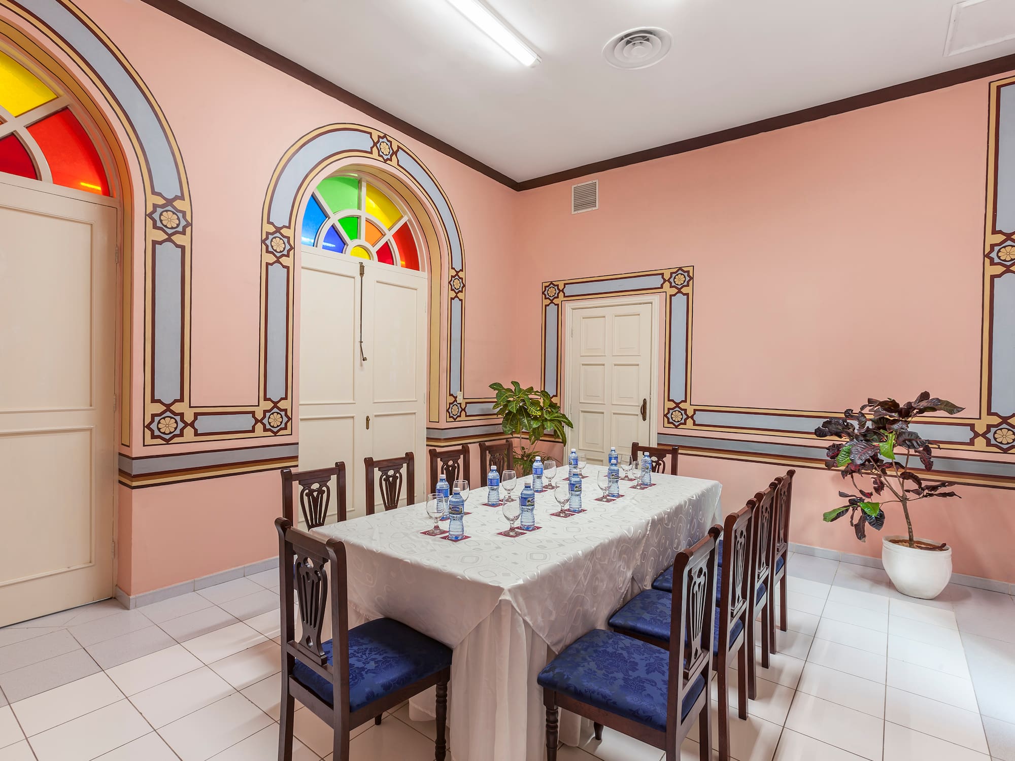 a table with chairs and a white tablecloth in a room with a pink wall