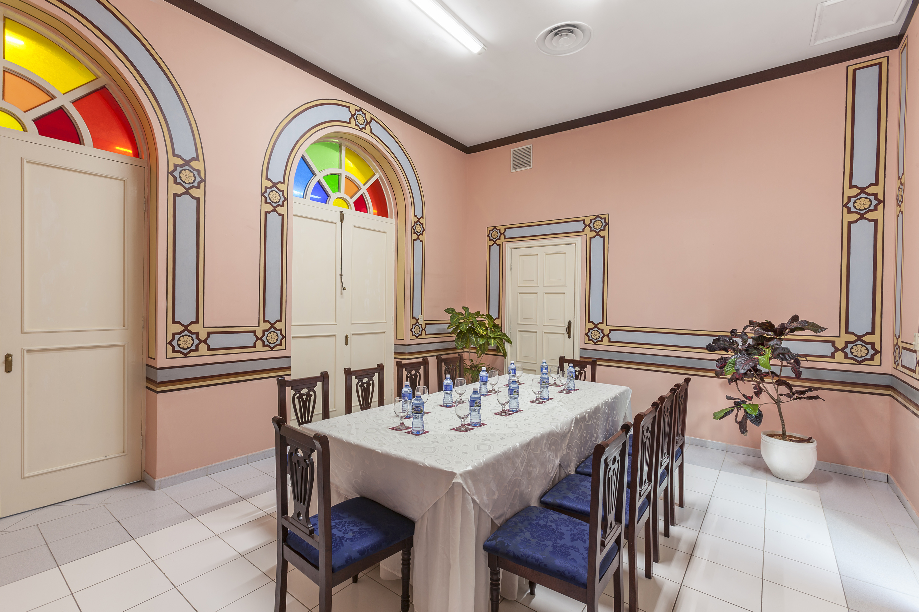 a table with chairs and a white tablecloth in a room with a pink wall