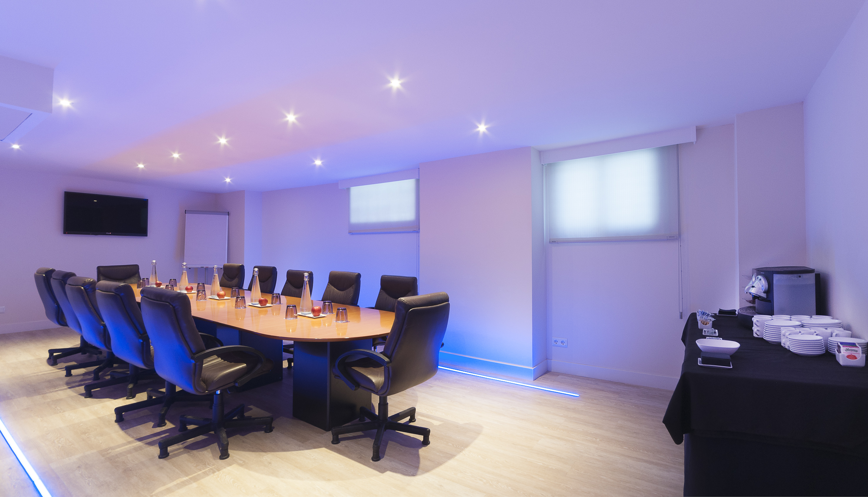 Modern boardroom with blue ambient lighting and full conference setup.