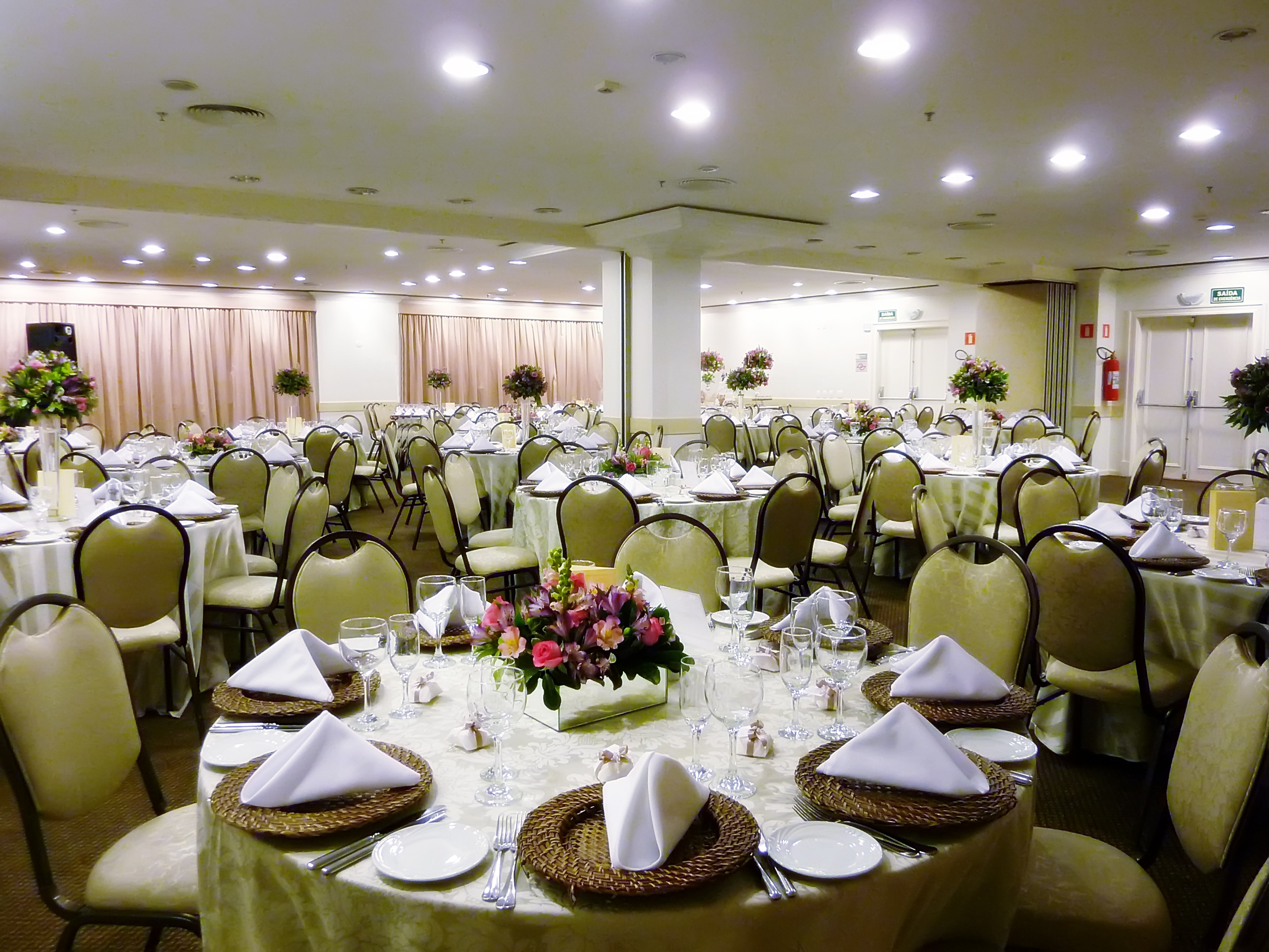 Elegant banquet hall with round tables, floral centerpieces, and formal place settings.