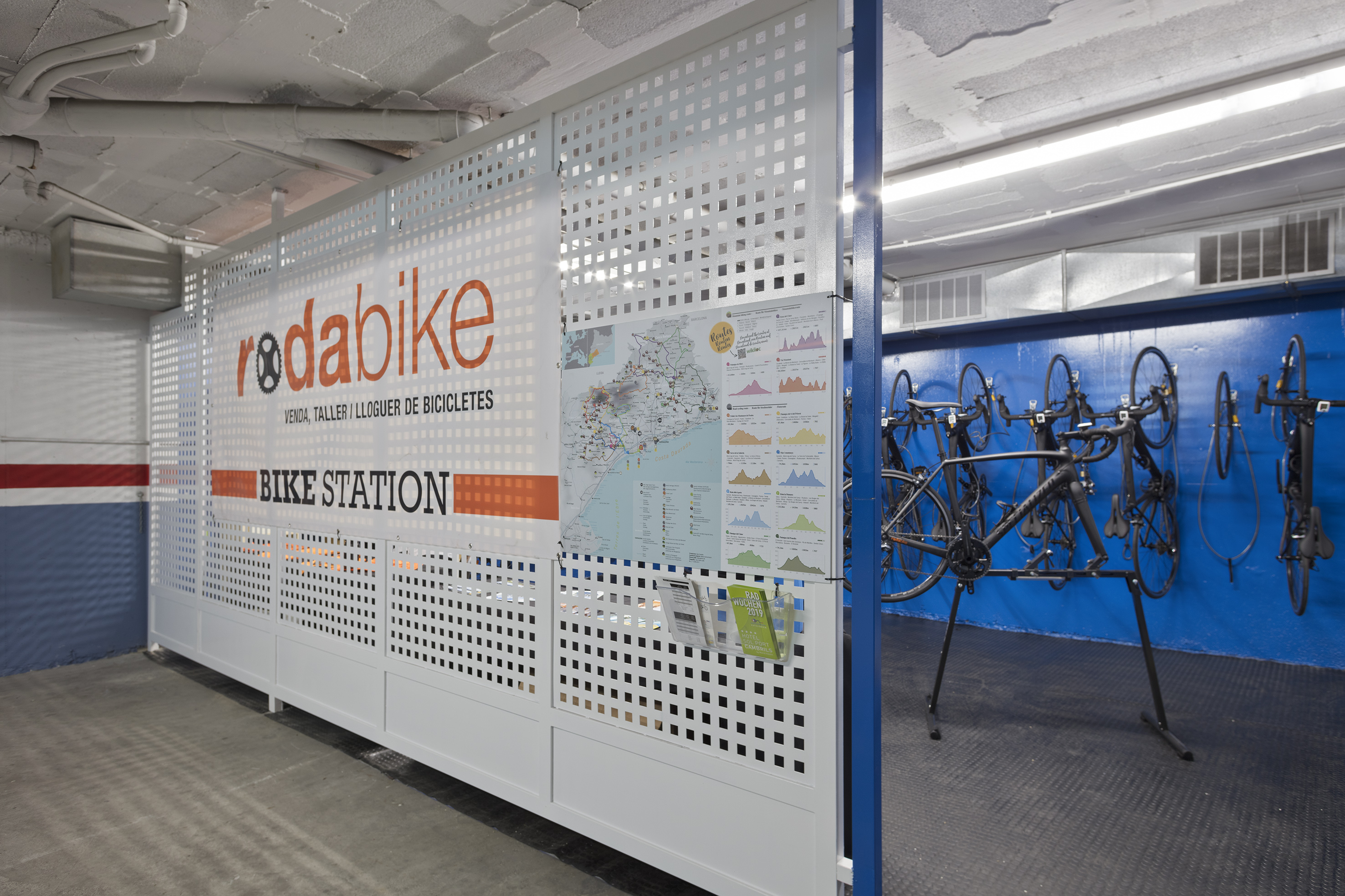 Rodabike Bike Station sign on white wall, with bike repair and rental area.