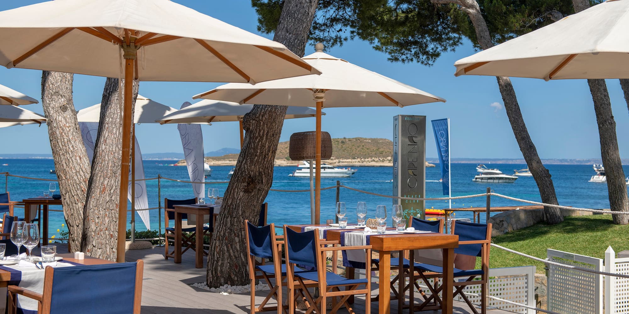 a table and chairs under umbrellas on a deck by a body of water