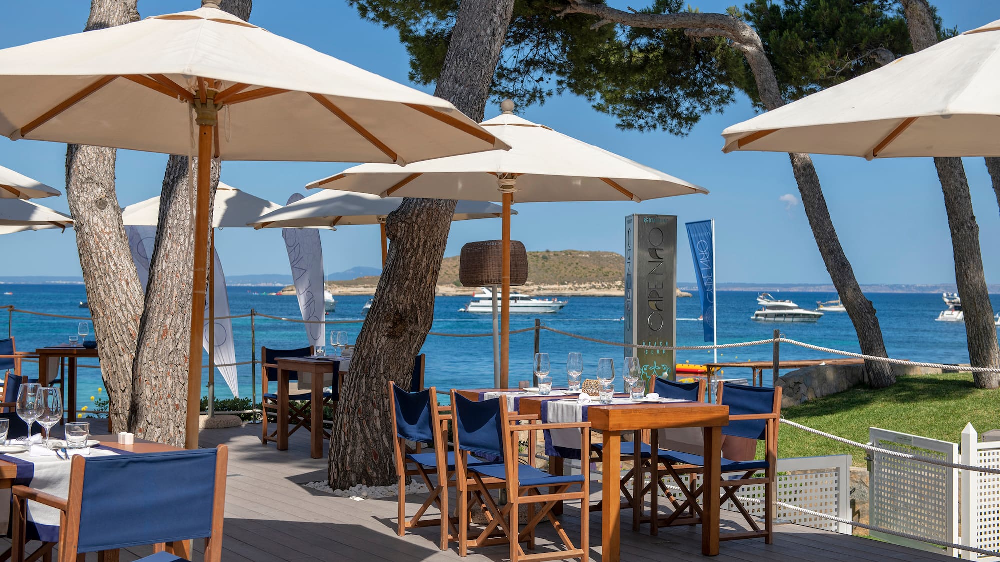 a table and chairs under umbrellas on a deck by a body of water
