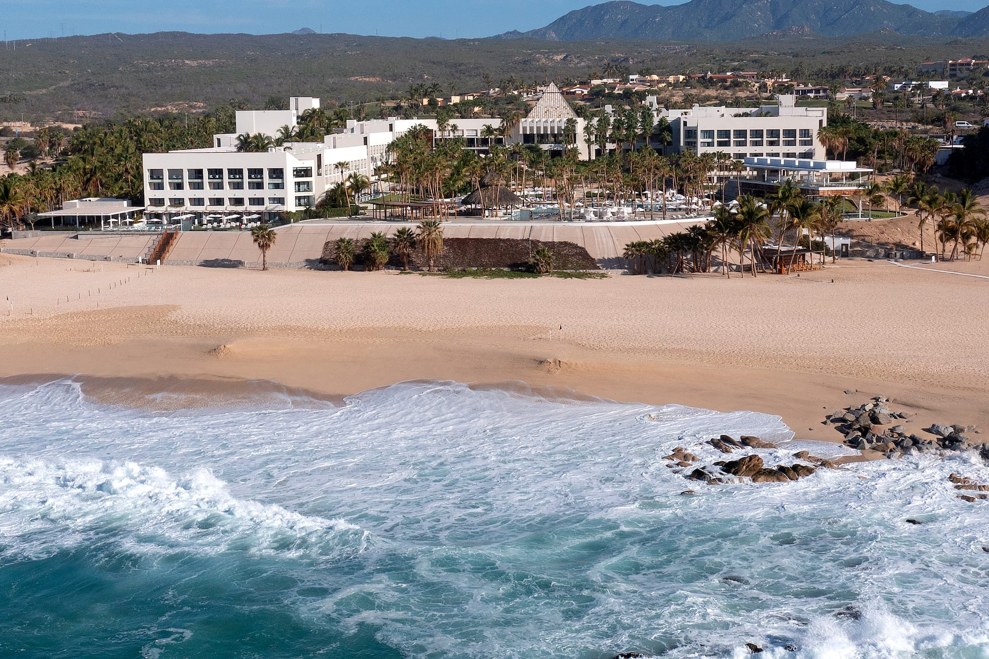 a beach with a building and waves crashing on it