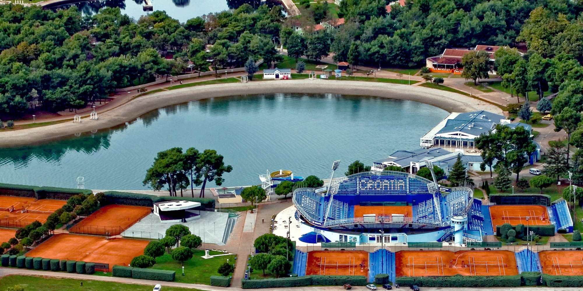 a large body of water with a stadium and trees