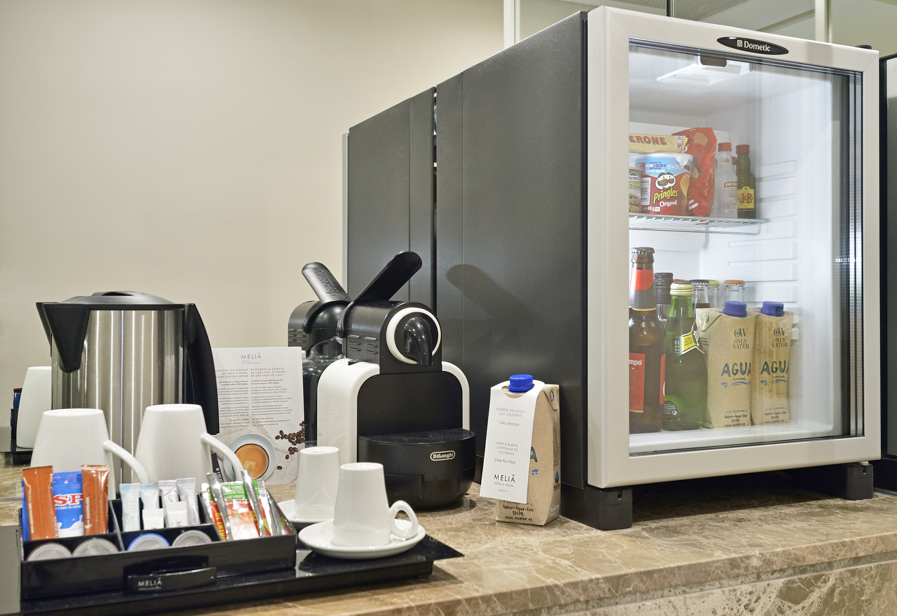 Melia hotel minibar and coffee station with kettle, drinks, and snacks.