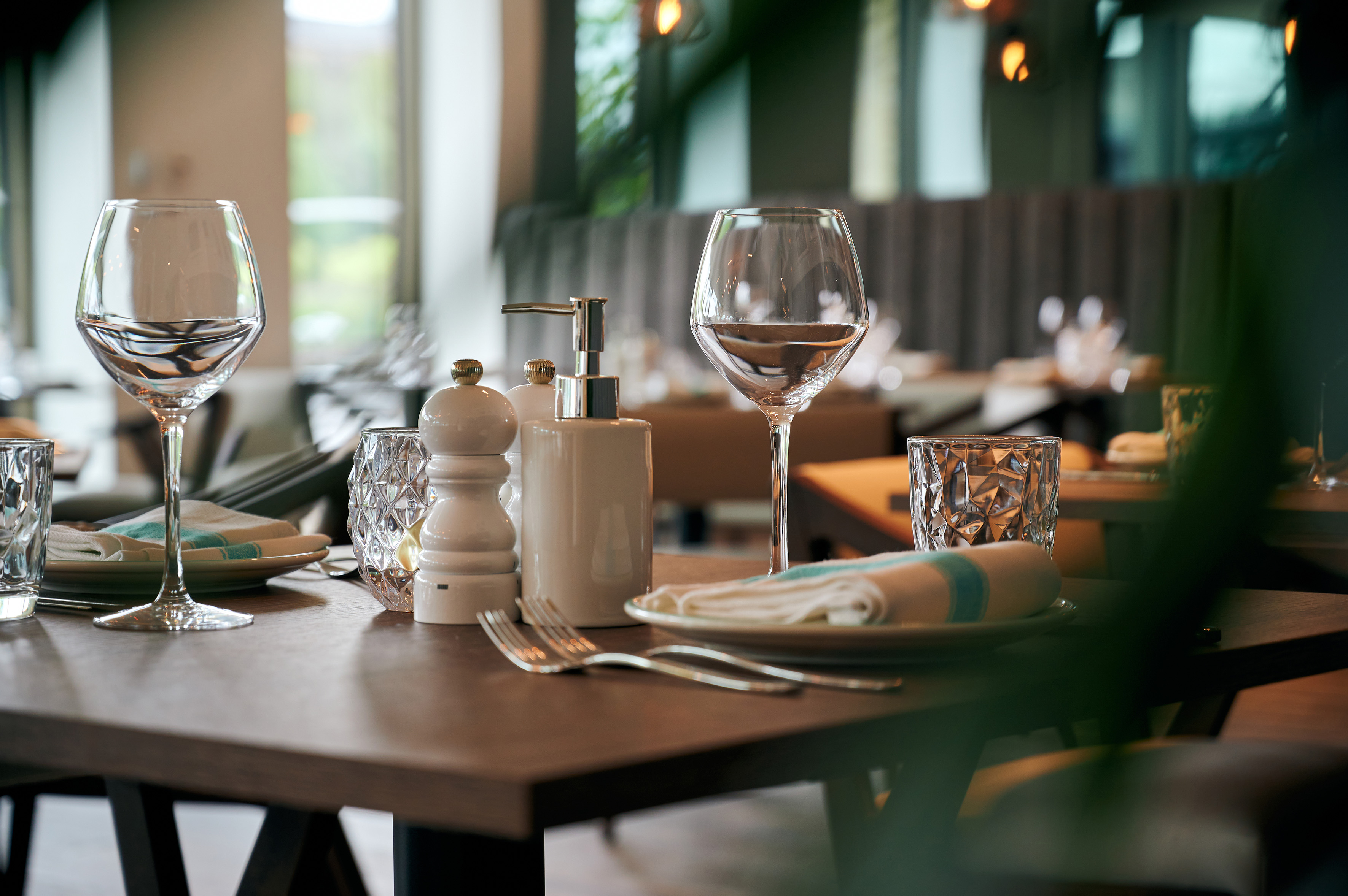 Modern restaurant table setting with wine glasses, plates, and cutlery.