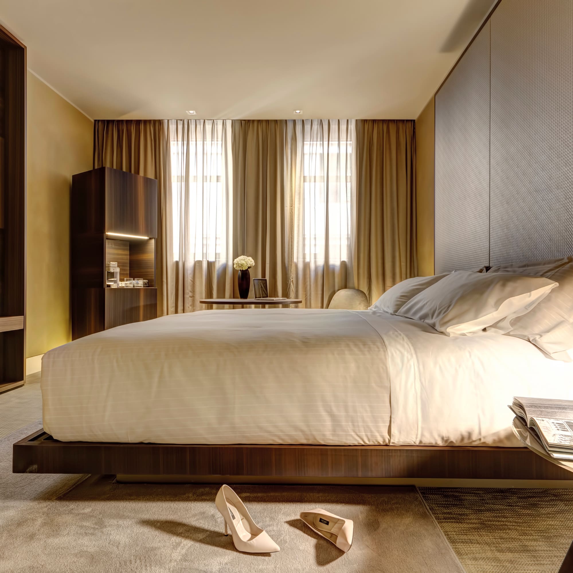 Modern luxury hotel bedroom with large bed, dark wood decor, and TV.