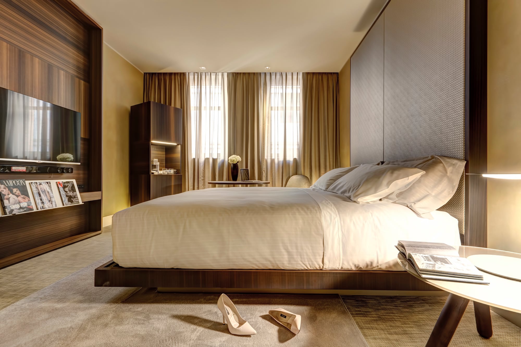Modern luxury hotel bedroom with large bed, dark wood decor, and TV.