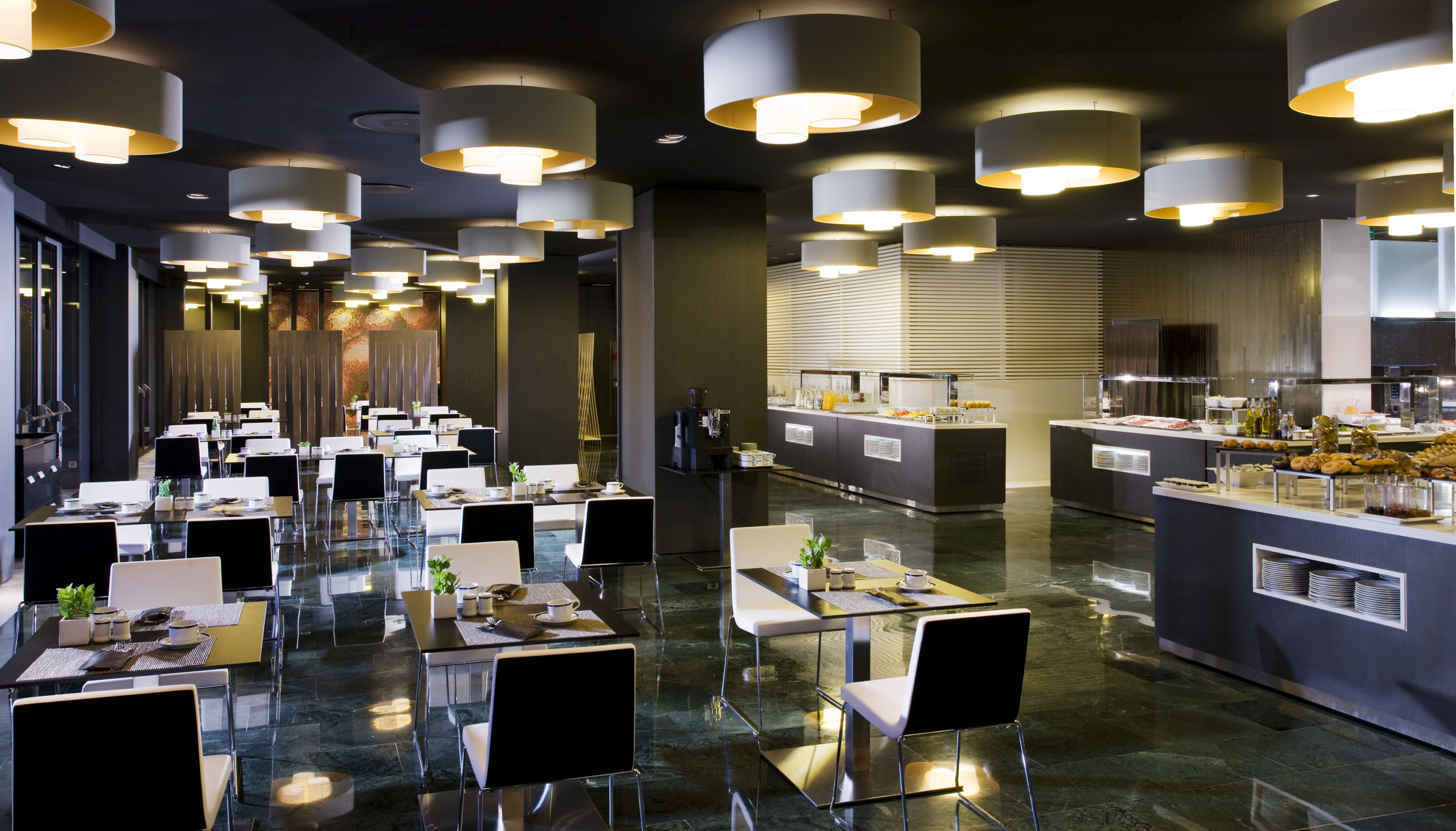 Modern restaurant dining room with breakfast buffet and elegant lighting.