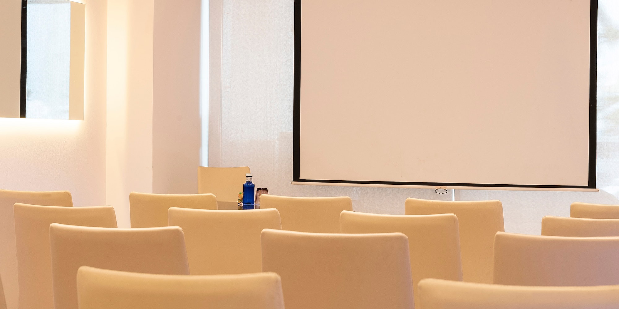 a room with white chairs and a projector screen