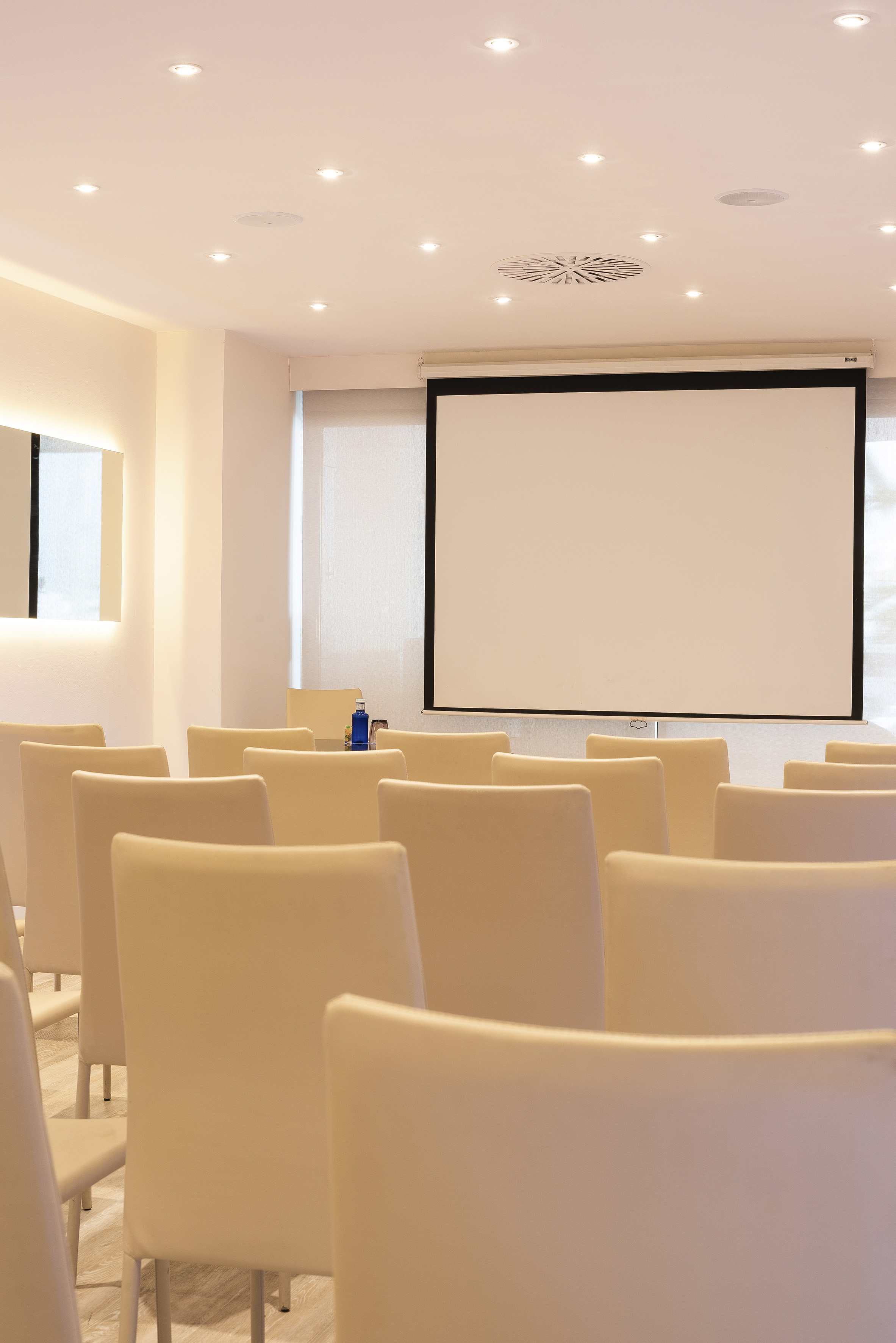 a room with white chairs and a projector screen