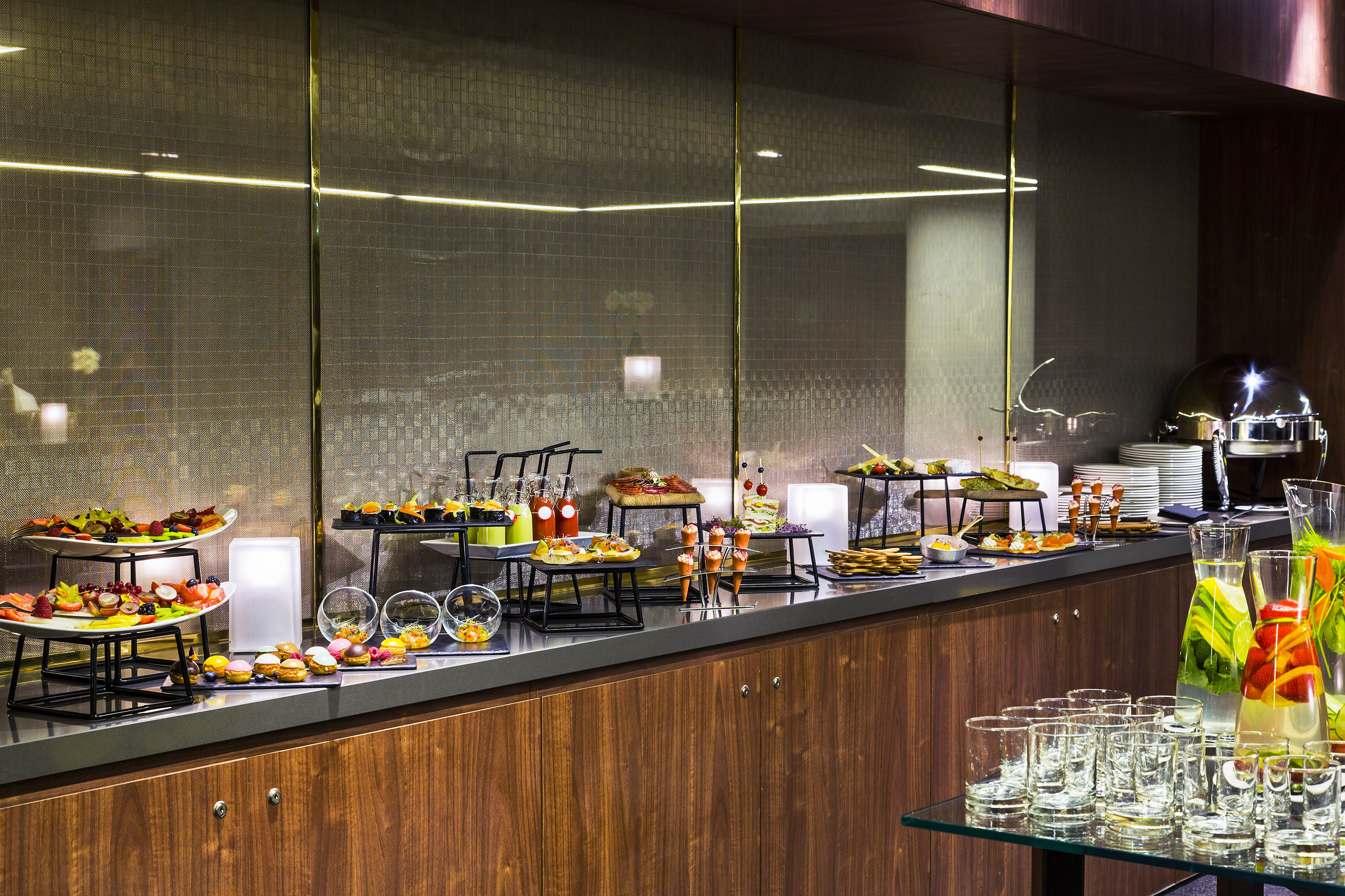 Modern catering buffet with diverse appetizers, desserts, and fresh drinks.