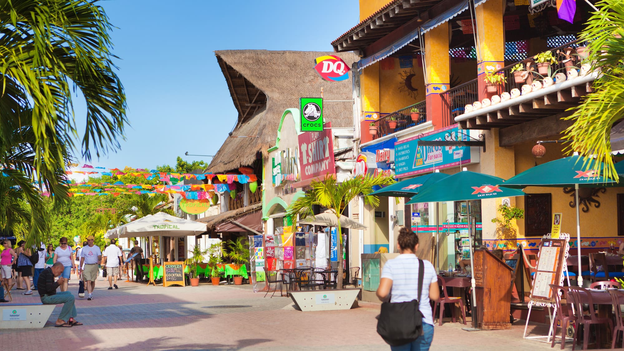a woman walking down a street with colorful signs and umbrellas