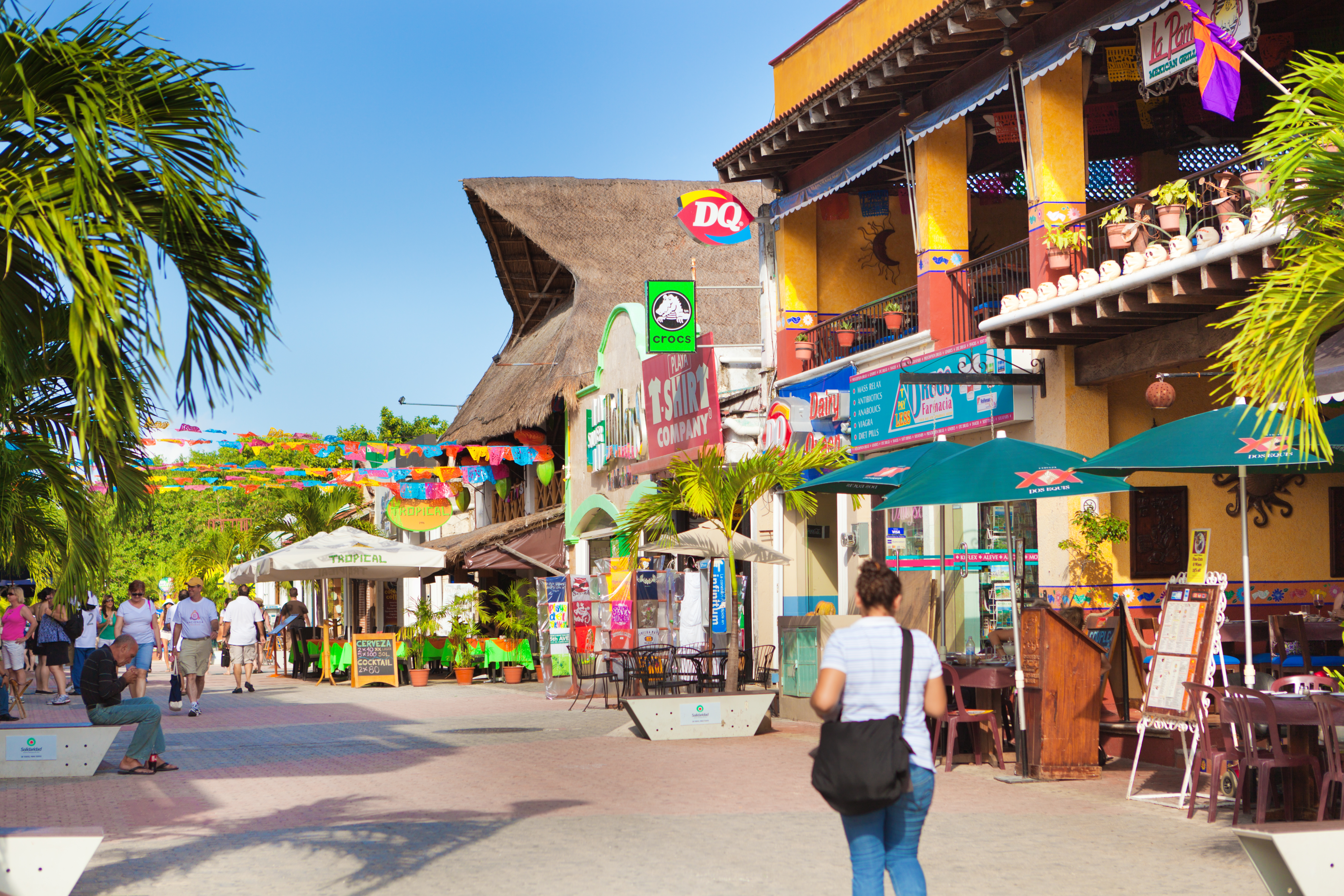 a woman walking down a street with colorful signs and umbrellas