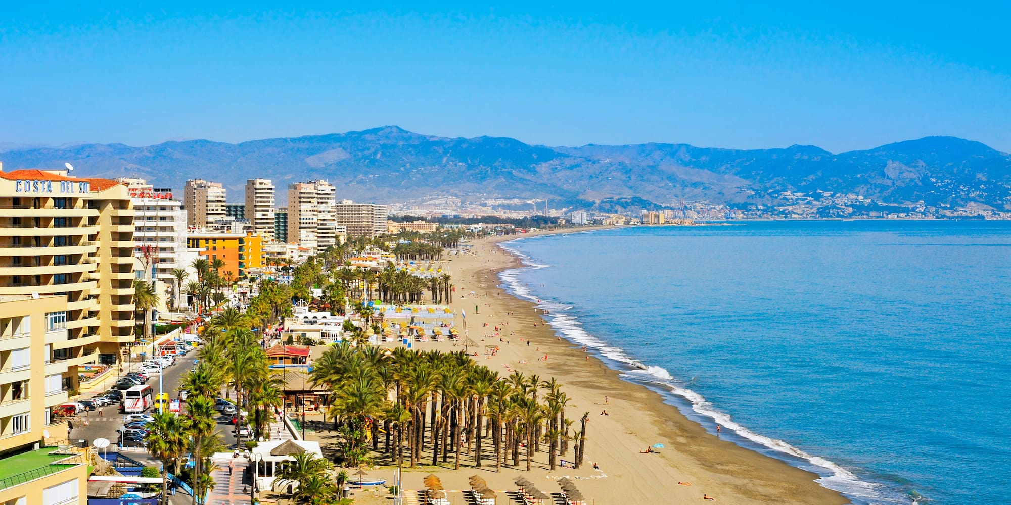 Sunny Costa del Sol beach, hotels, palm trees, ocean, and mountains.