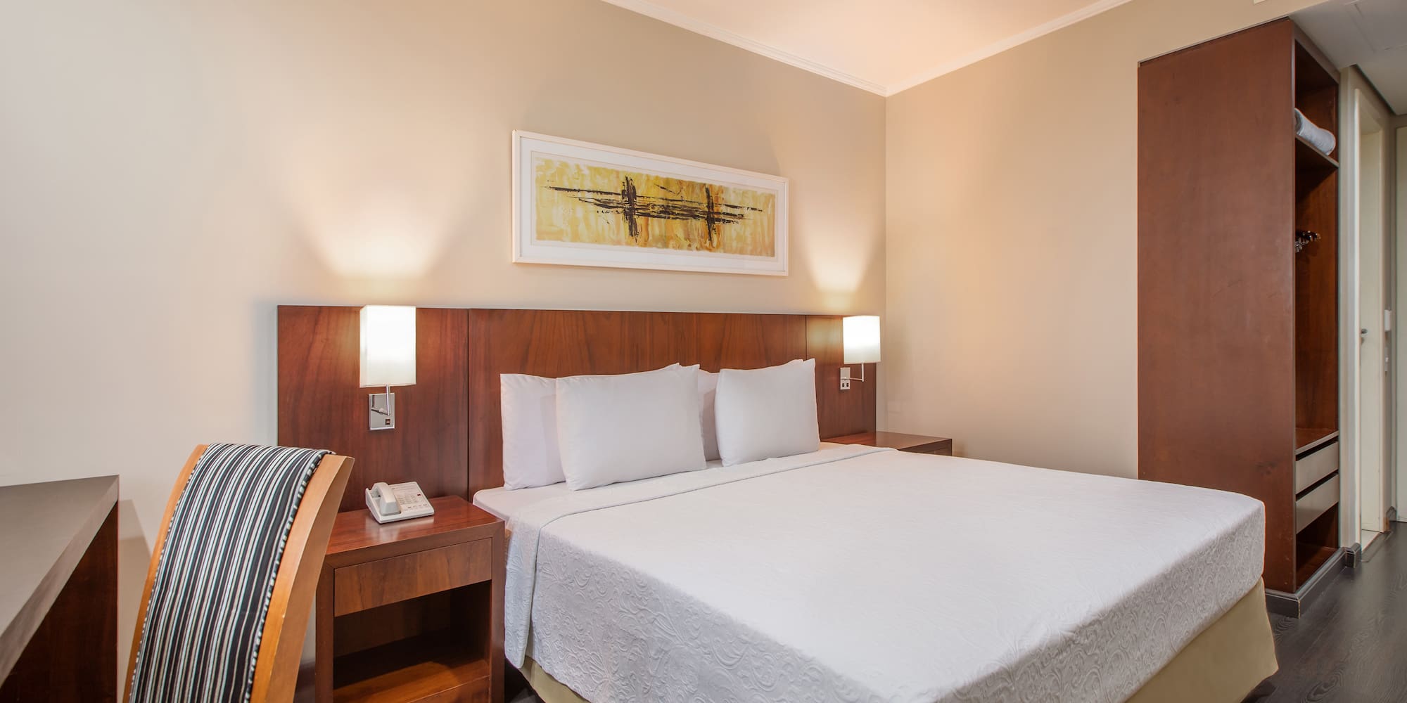 a bed with white sheets and a wood headboard