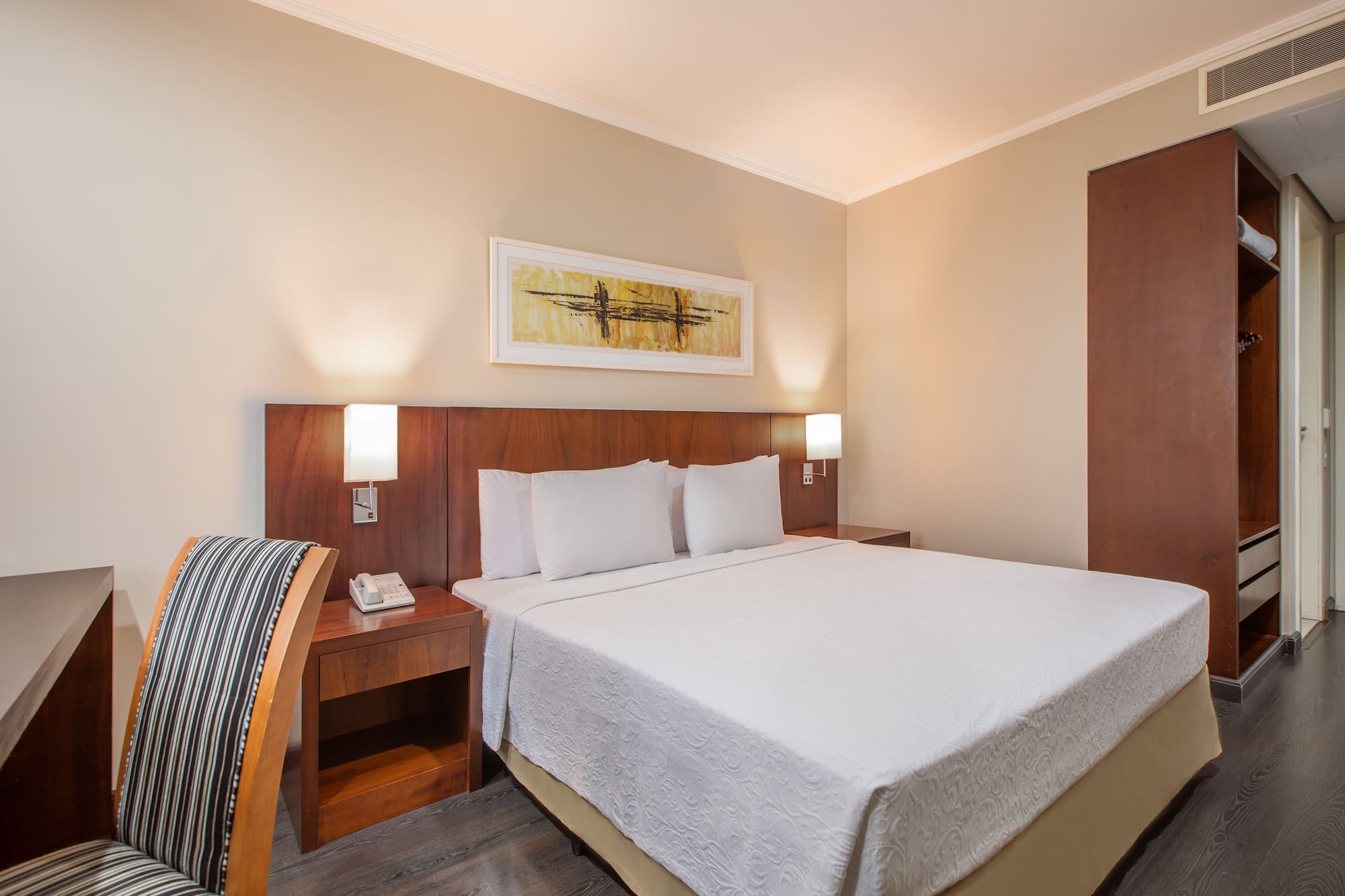 a bed with white sheets and a wood headboard