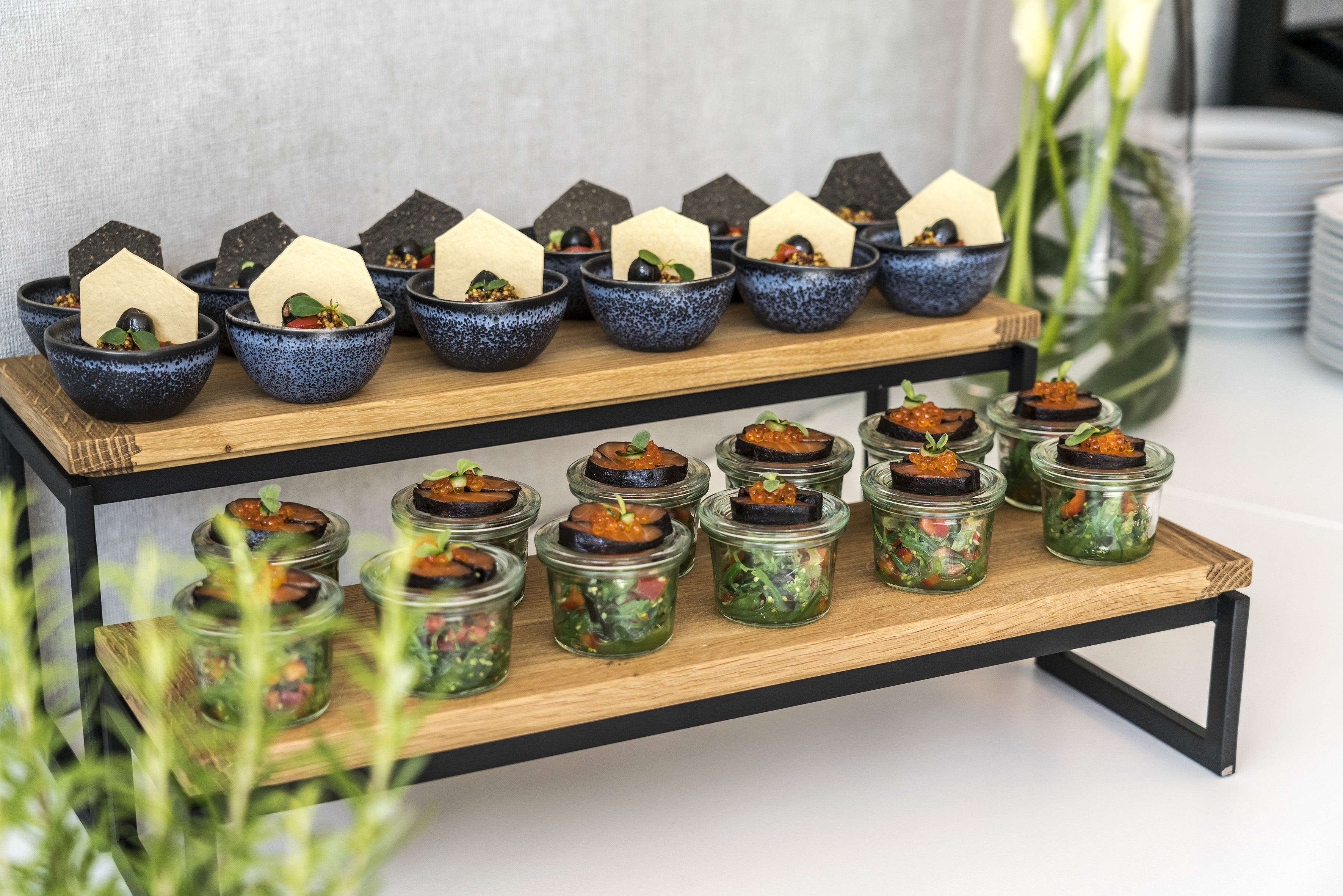 Gourmet appetizers served on a two-tier wooden catering stand.