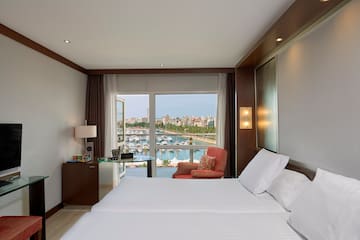 a room with a bed and a view of the water and a city