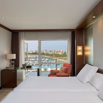 a room with a bed and a view of the water and a city