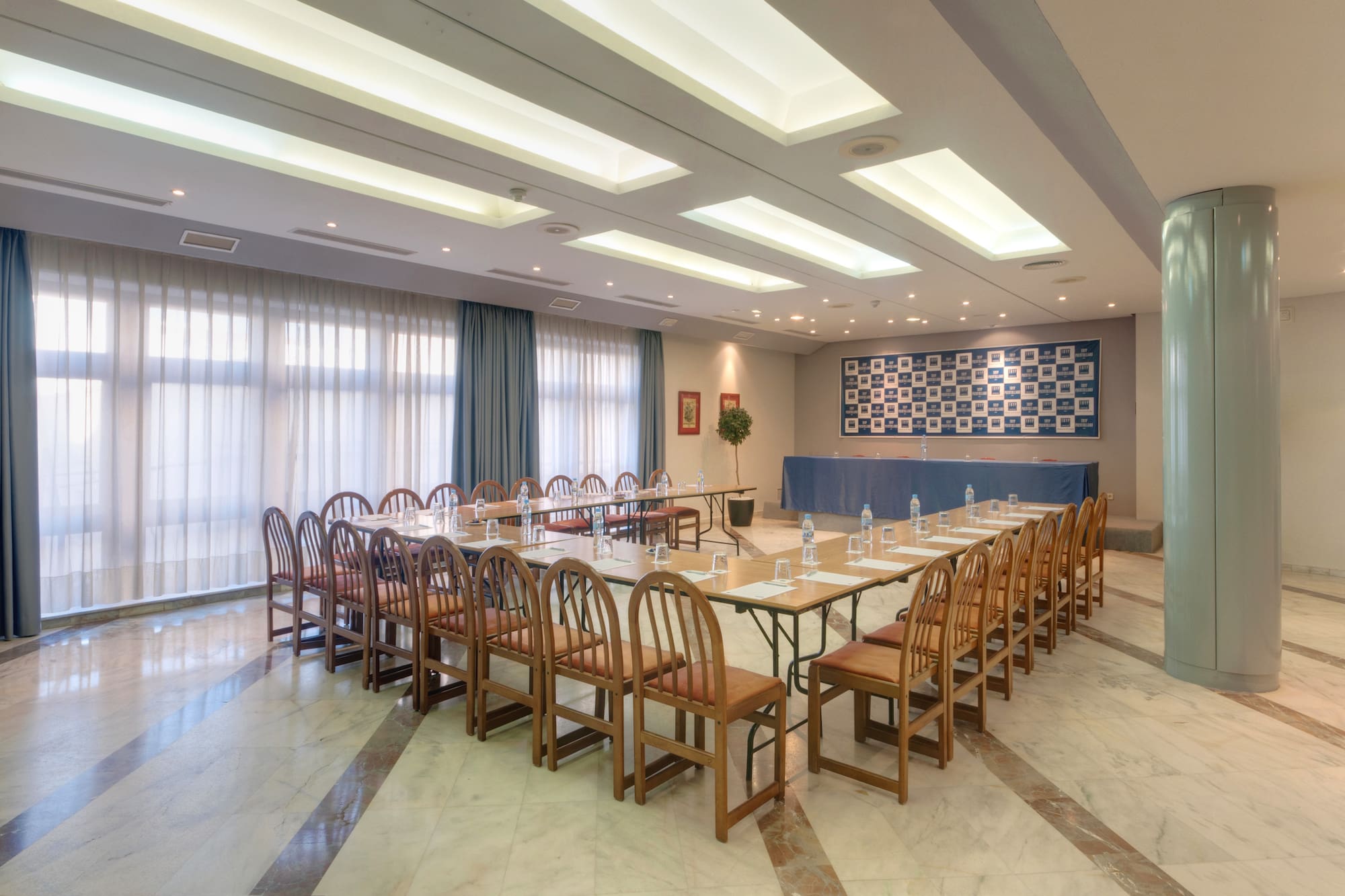 Bright conference room with U-shaped table, wooden chairs, and large windows.