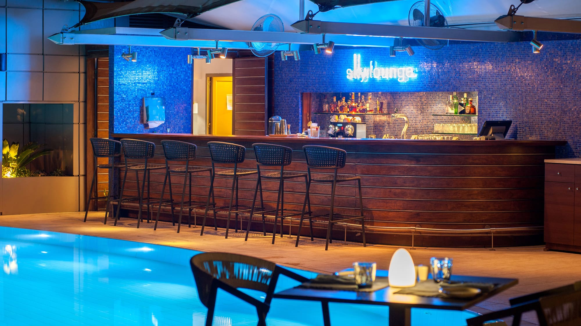 a bar with chairs and a pool at night